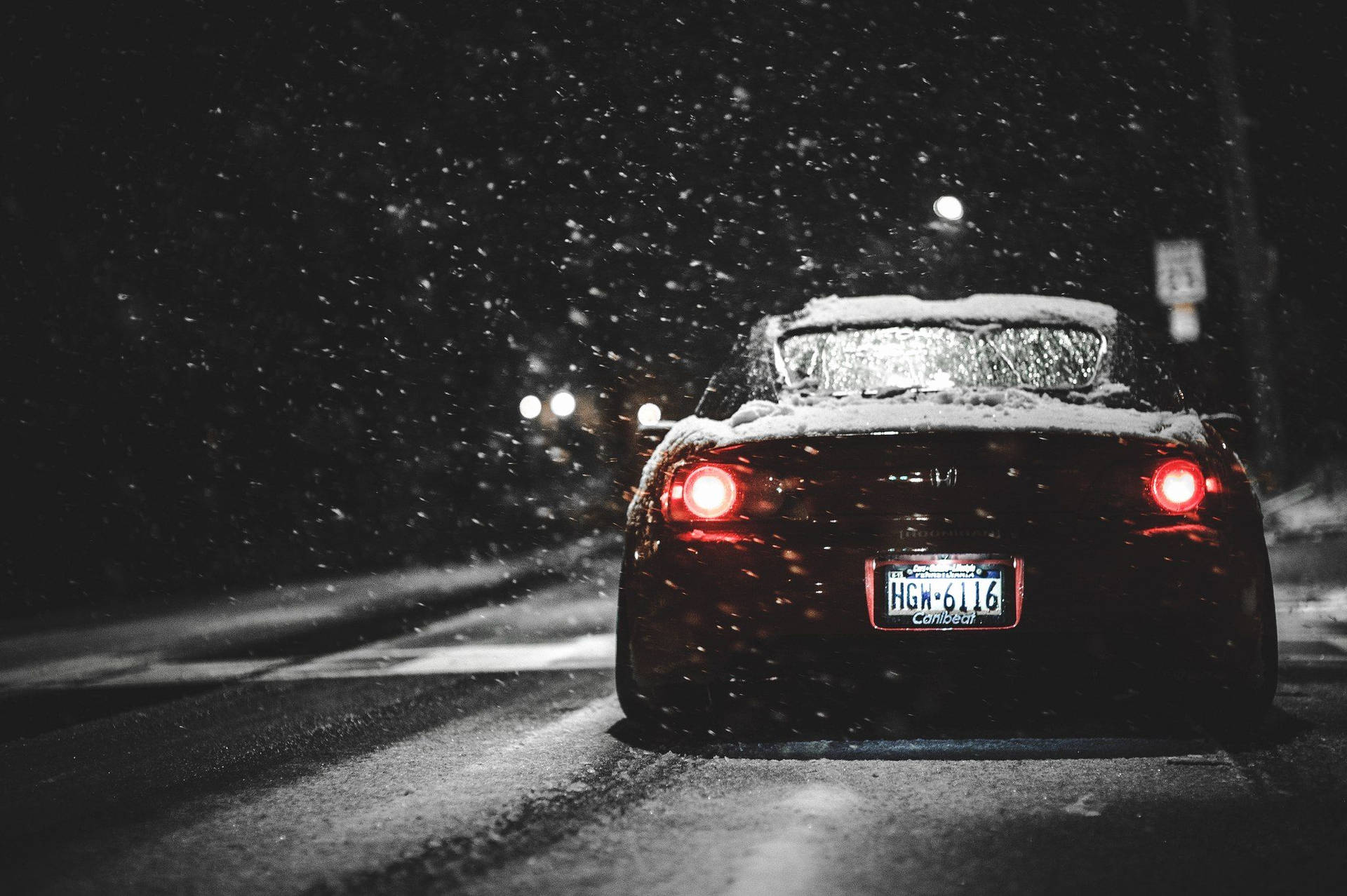 一輛沾滿雪的汽車在夜間暴風雪中行駛的紅色尾燈。 — 4K Jdm 壁紙