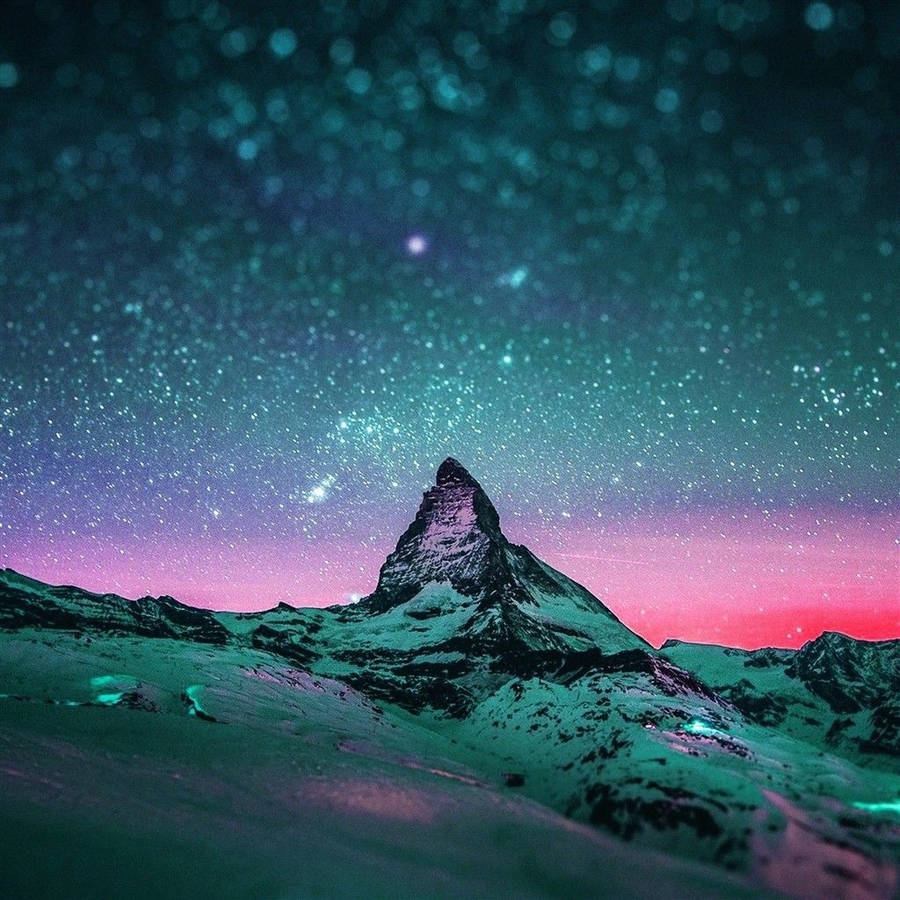積雪的山峰在星空下，青綠色和粉紅色的天空中有發光的極光。 — iPad 壁紙