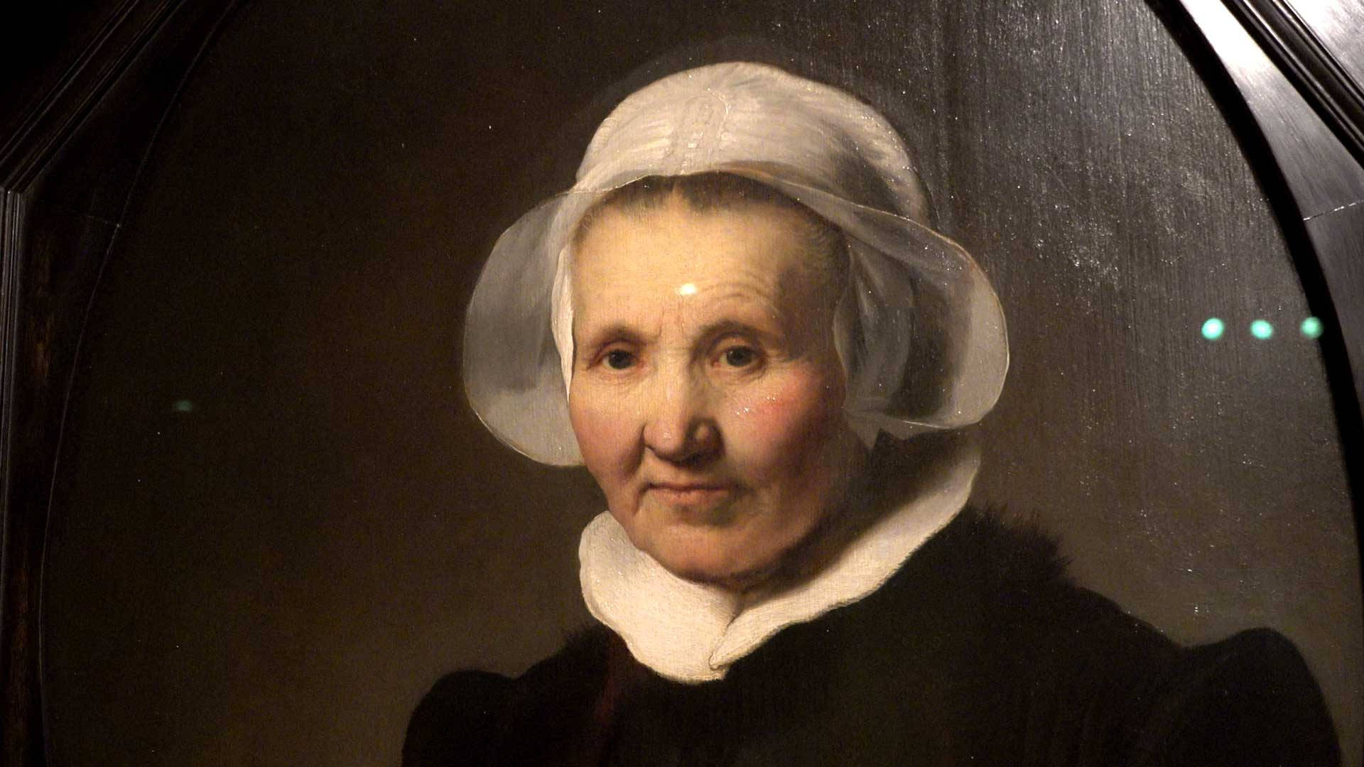 Rembrandt 桌布 壁紙 — 17世紀油畫特寫，描繪一位戴白帽、穿深色連衣裙的老婦人，背景為深色。