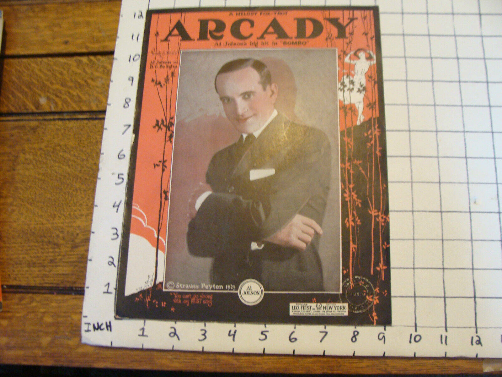 手機 桌布 壁紙 — 1925年復古《Arcady》雜誌封面，一名微笑的西裝男子坐在木桌上，桌上放有尺子。
