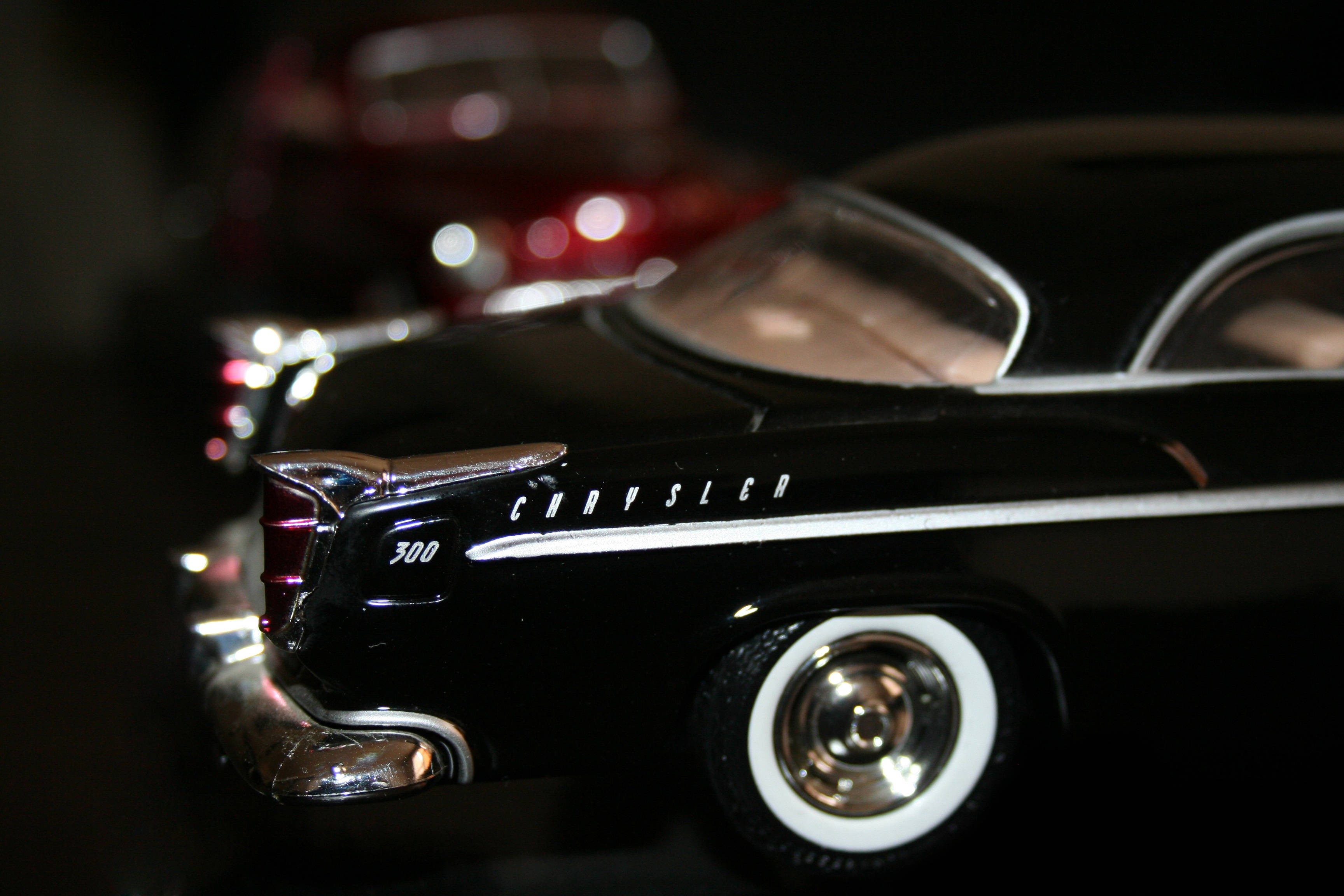 復古 桌布 壁紙 — 1950年代光澤黑色Chrysler 300模型車的特寫，帶有鍍鉻飾邊和白色側壁輪胎，在戲劇性的夜間燈光下。
