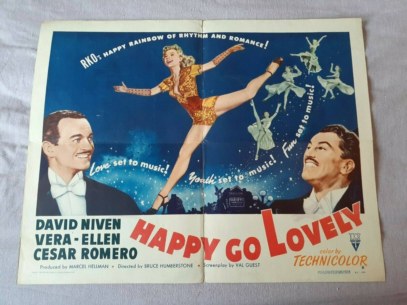 電影動圖 桌布 壁紙 — 1950年代復古電影海報《Happy Go Lovely》，描繪一位快樂的舞者和兩位微笑的演員，背景是星光閃爍的藍色夜空。