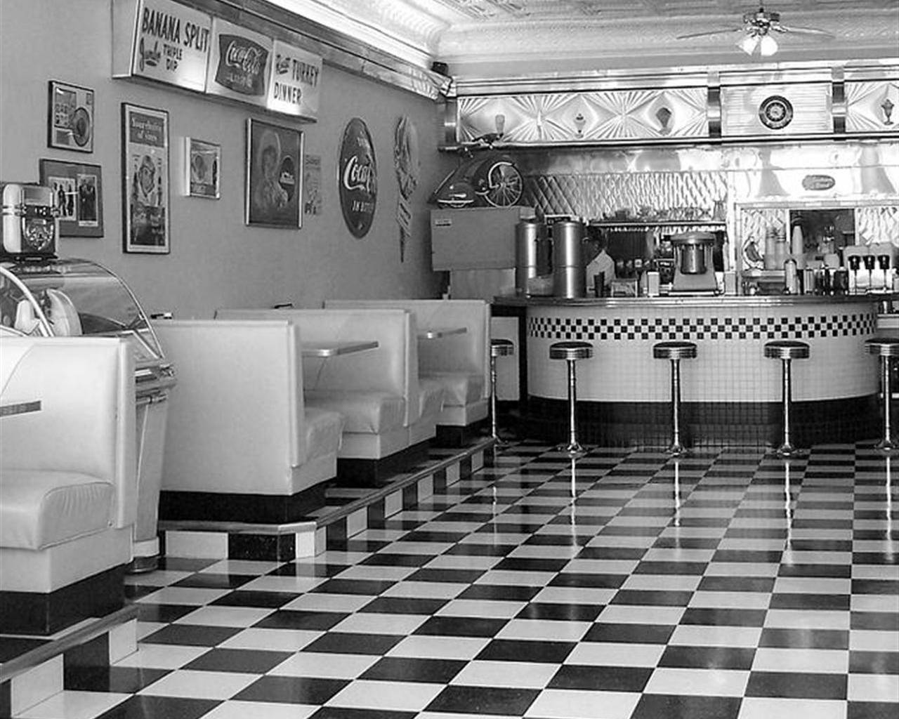 Diner 桌布 壁紙 — 1950年代復古餐廳內部，設有格子地板、卡座和復古可口可樂標誌。