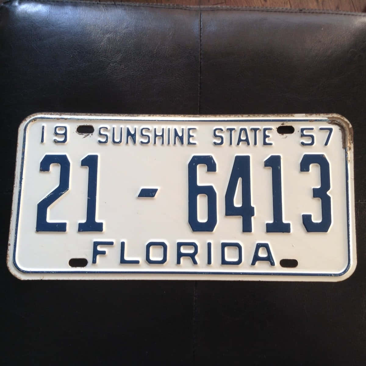 License Plate 桌布 壁紙 — 1957年佛羅里達州復古車牌（號碼21-6413）放置在深色皮革表面上，顯示磨損痕跡。