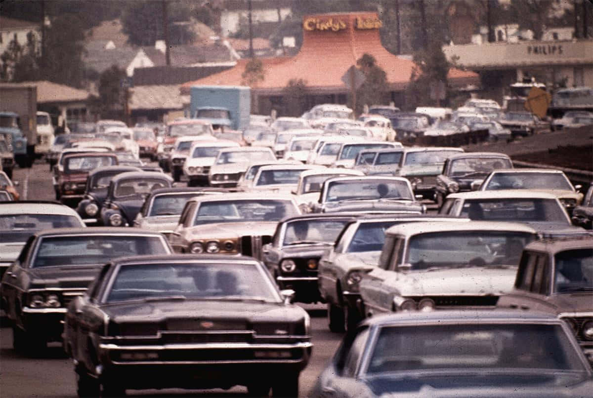 1970s 桌布 壁紙 — 1960年代的交通堵塞，充滿復古汽車在陽光普照的高速公路旁的路邊餐廳附近。