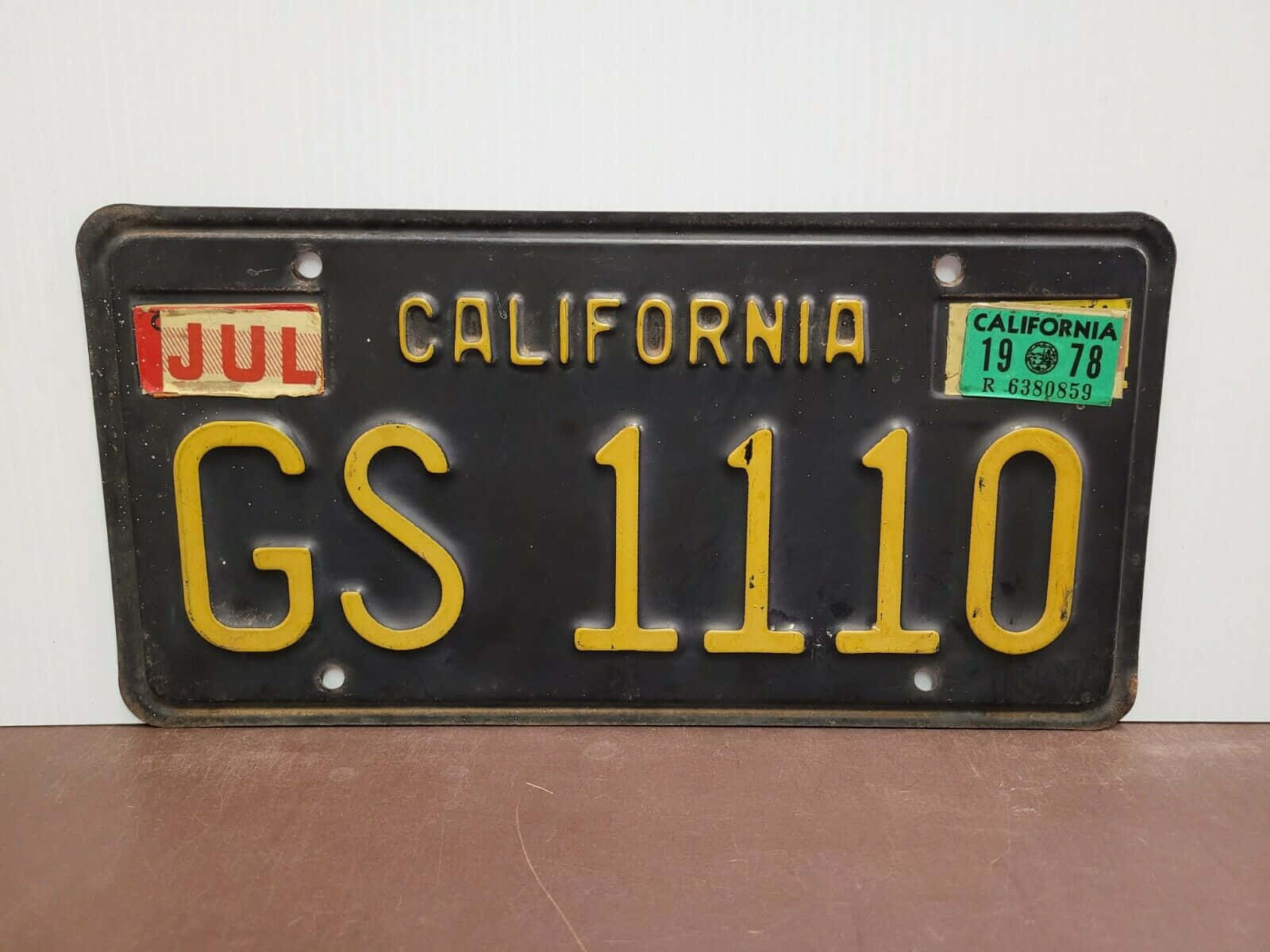 License Plate 桌布 壁紙 — 1978年加州復古車牌，黑色背景上帶有黃色字母，放置在木質表面上。