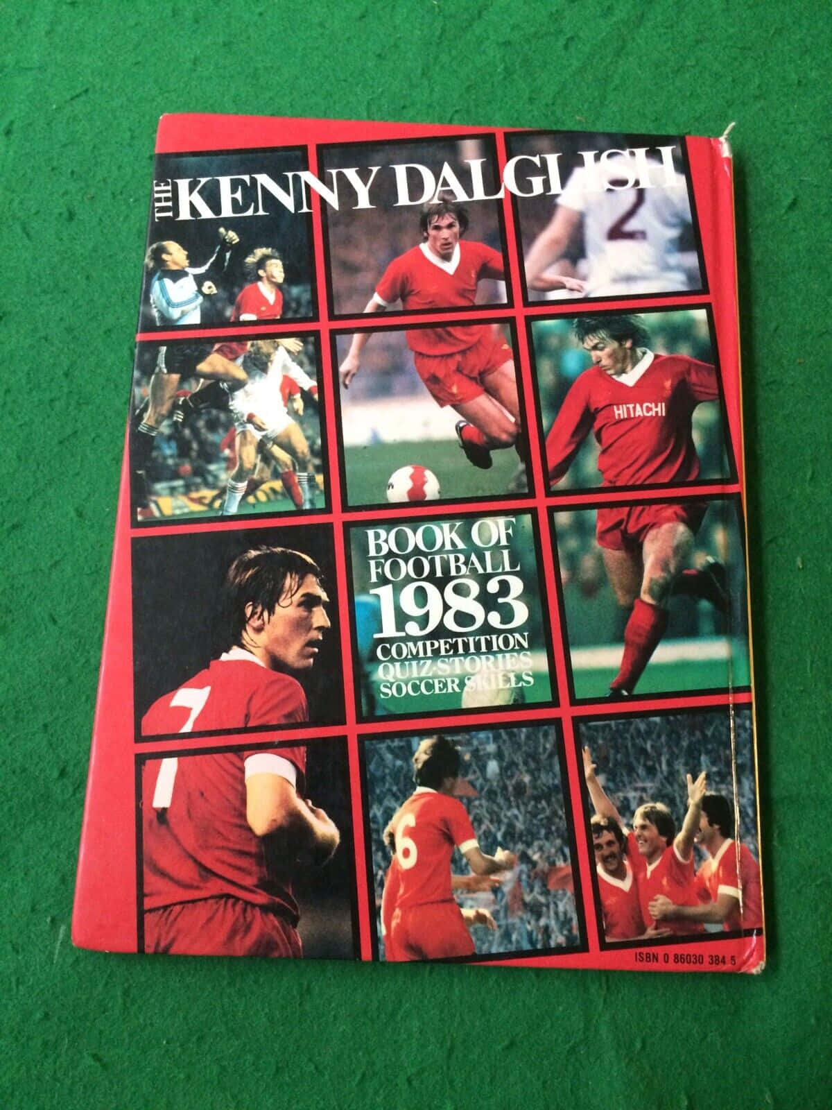足球 桌布 壁紙 — 1983年復古足球書， featuring Kenny Dalglish 身穿紅色利物浦球衣，在綠色氈背景上展現動態動作鏡頭。