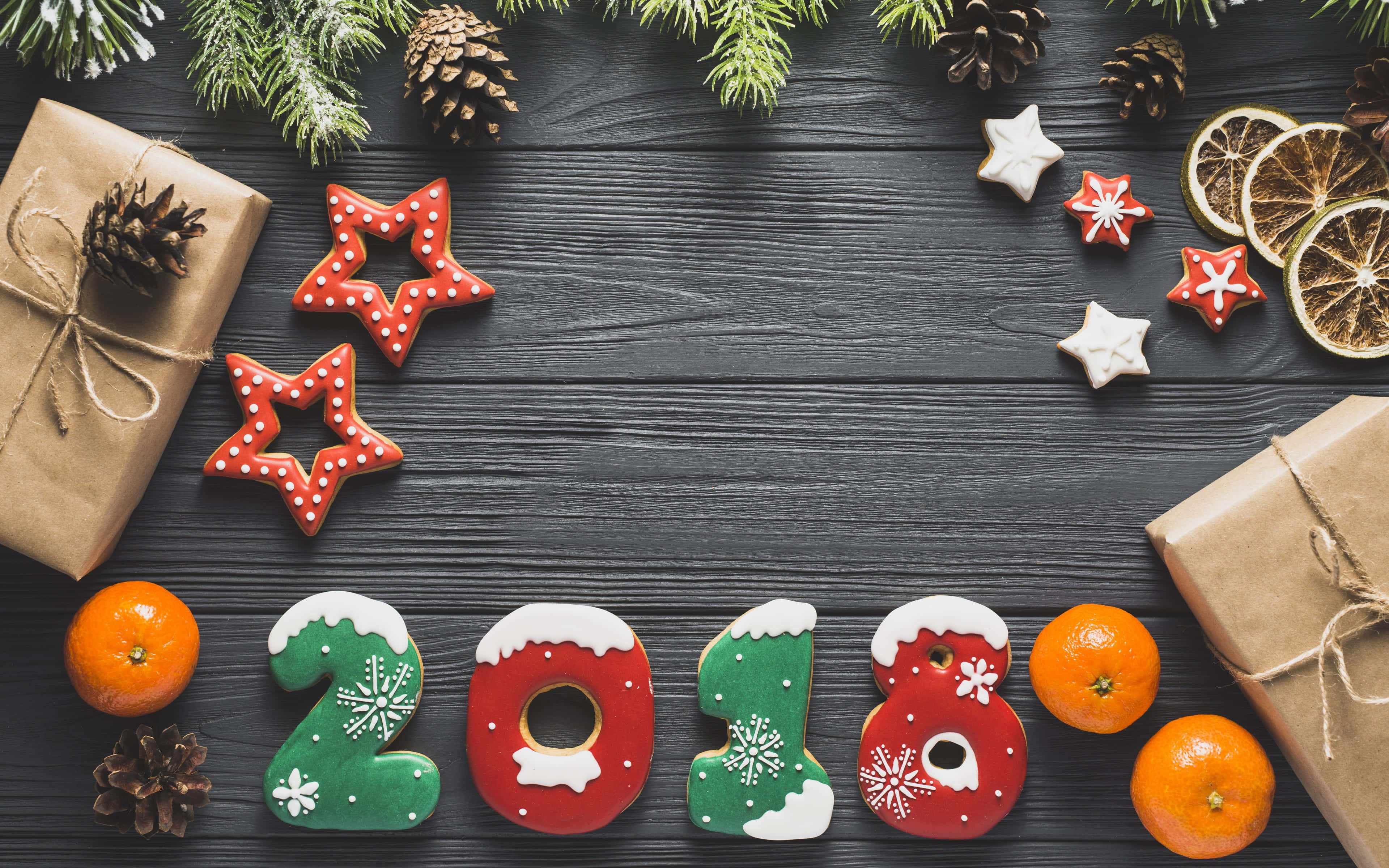 2018 桌布 壁紙 — 2018年節日薑餅餅乾以數字和星星形狀排列在深色木桌上，搭配松果、乾橙和包裝好的禮物。