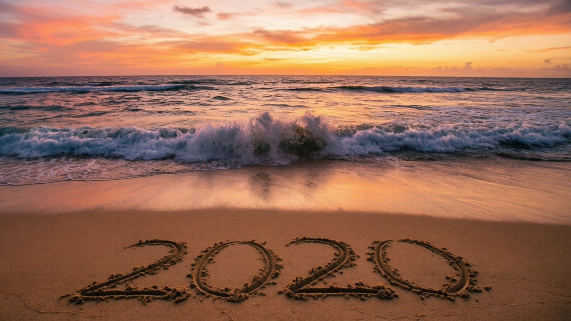 Beach 2020 Sunset 壁紙 — 2020年寫在海灘的沙上，海浪在火紅的日落天空下拍打。