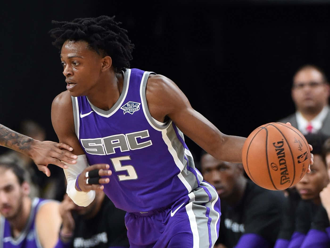 紫色球衣的籃球運動員在比賽中運球，附近有防守球員。 — NBA 壁紙