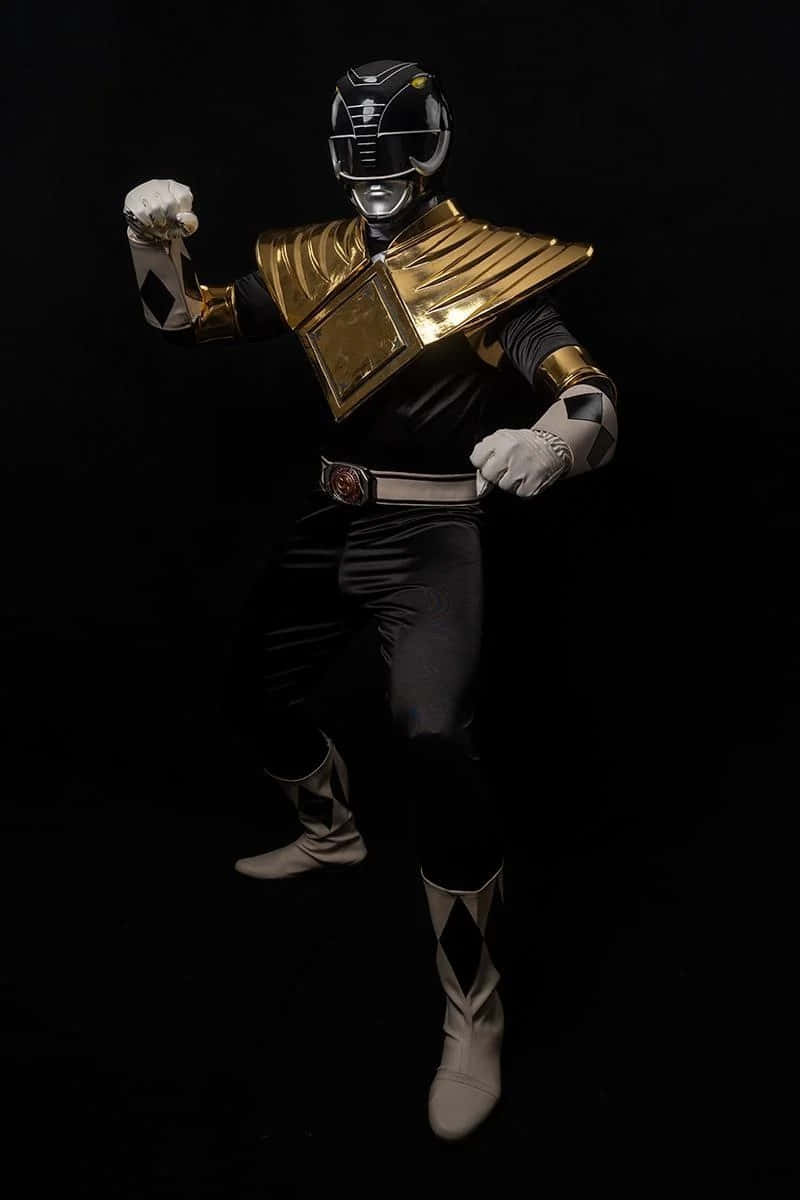  壁紙 — 一個黑金配色的Power Ranger在純黑背景前擺出動感姿勢，搭配戲劇性燈光。