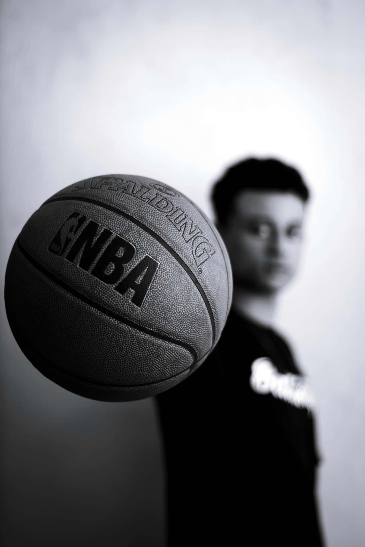  壁紙 — NBA Spalding 籃球的黑白特寫，背景中有一個模糊的人影。