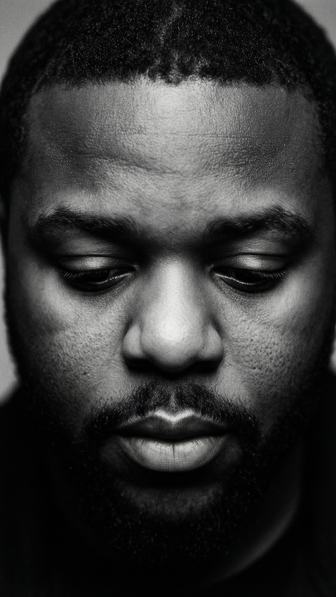 Contemplative J. Cole Portrait 壁紙 — 一個閉上眼睛、沉思表情的男人的黑白特寫肖像。