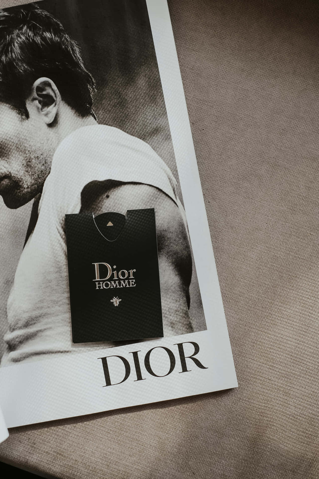  壁紙 — 一則黑白Dior Homme香水廣告，男士側臉置於有紋理的米色表面上。