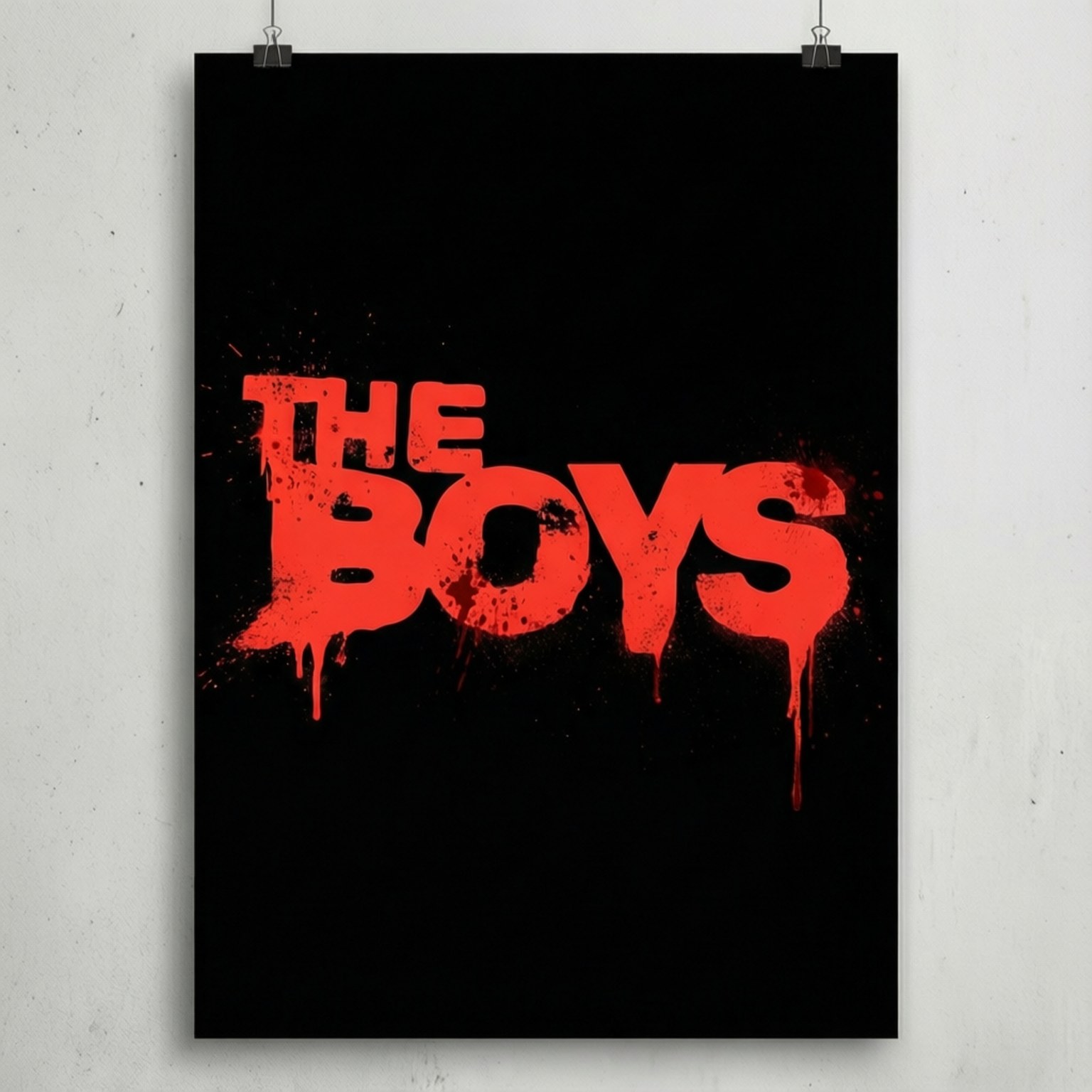 Minimalist Poster 壁紙 — 一張黑色海報，上面有粗體紅色滴落文字寫著「THE BOYS」，用兩個銀色迴紋針夾在白色牆上。