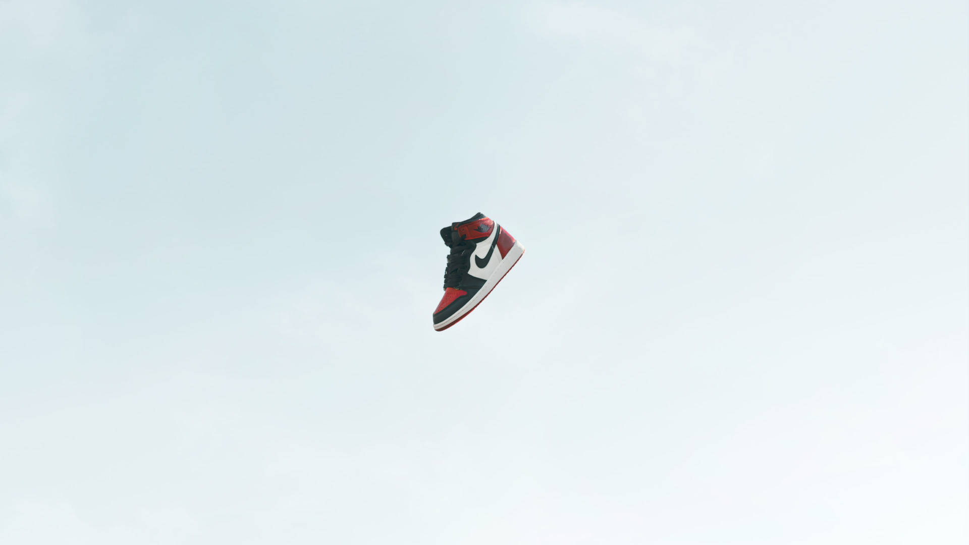 一隻運動鞋懸浮在雲層之上的天空中。 — Air Jordan 壁紙