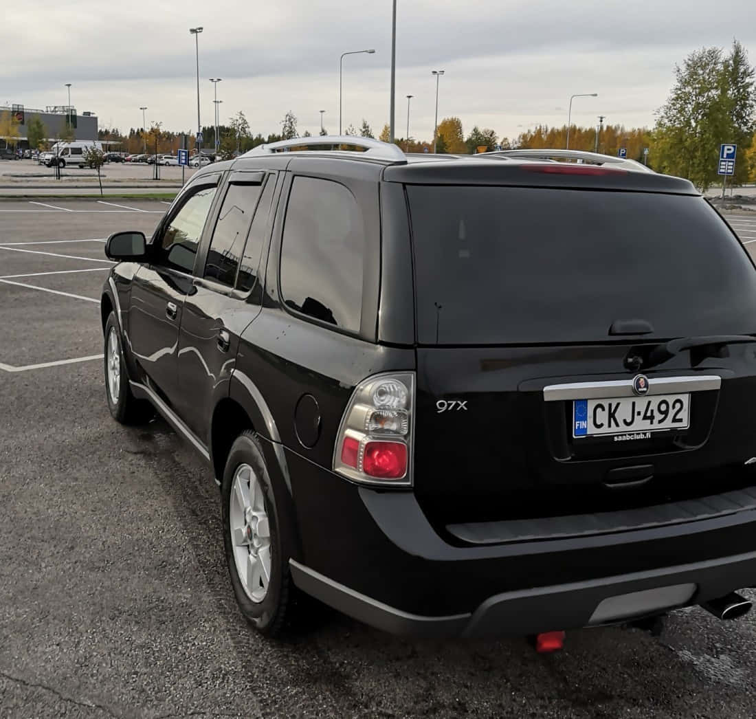 Saab 9-7x 桌布 壁紙 — 一輛黑色薩博97x SUV停放在陰天的停車場，背景有秋天的樹木。