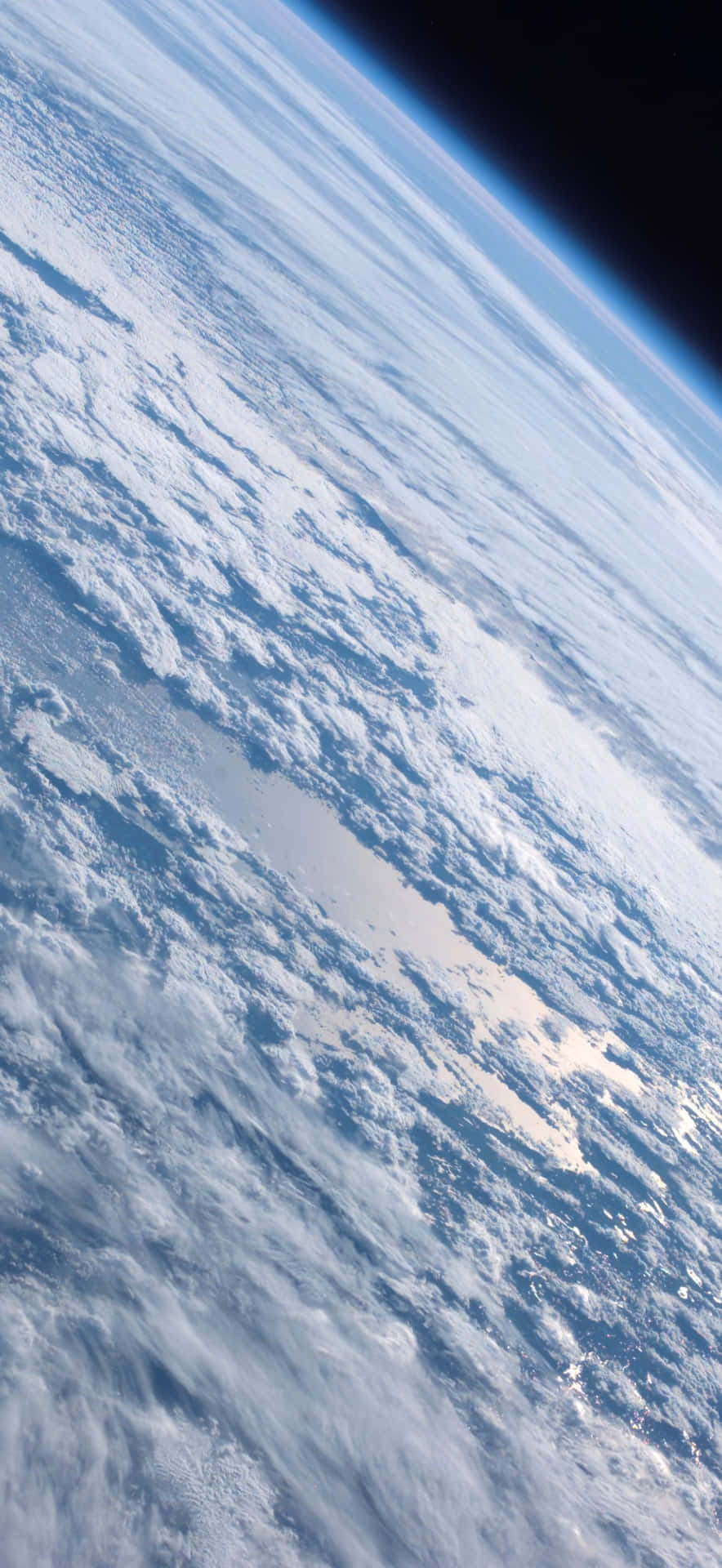  壁紙 — 從太空俯瞰地球的壯麗景色，展現藍色海洋和陸地上旋轉的白雲，沿著彎曲的地平線有一層薄薄的大氣輝光。