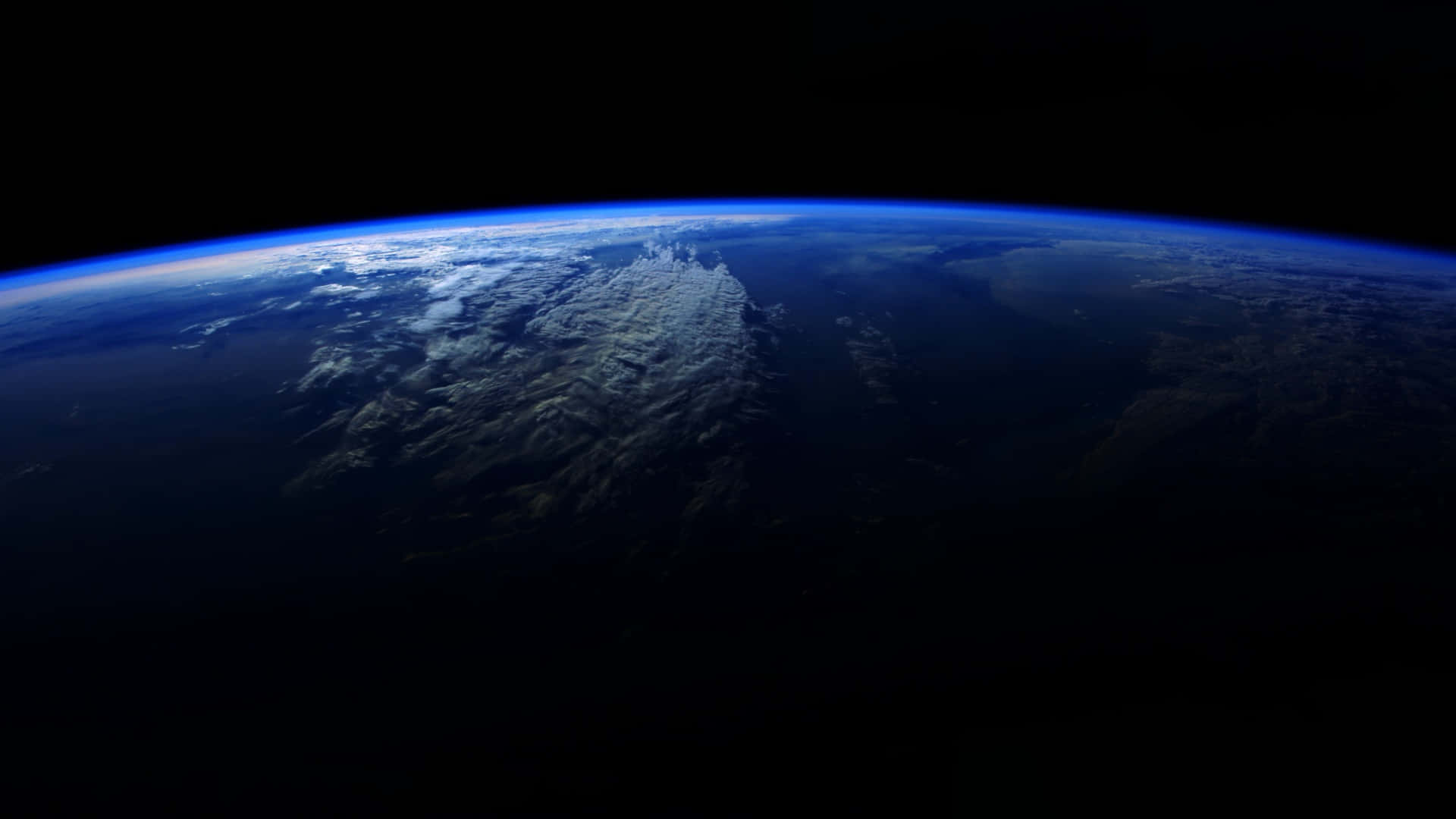  壁紙 — 從太空俯瞰地球彎曲地平線的壯麗景色，藍色海洋、白色雲層和深色陸地映襯著黑色虛空。