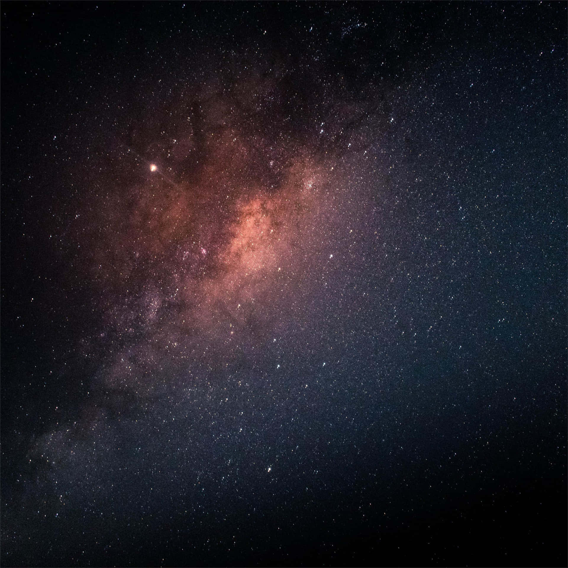 銀河系在夜空中閃耀著粉紅色和紫色的星雲，以及無數的星星。 — iPad 壁紙