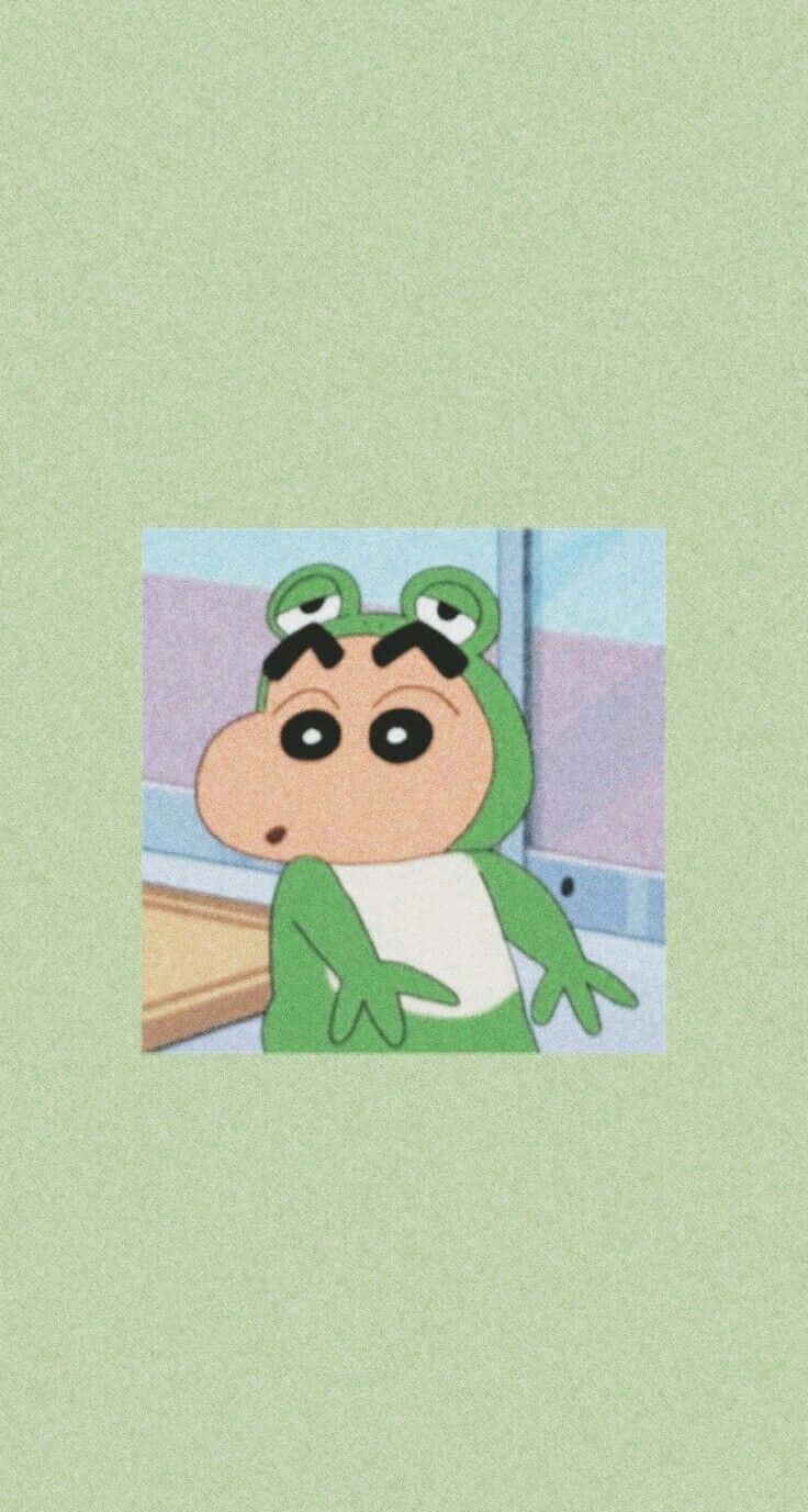  壁紙 — 一個穿著綠色青蛙服裝、有大眼睛和粗眉毛的卡通角色站在柔和背景前。