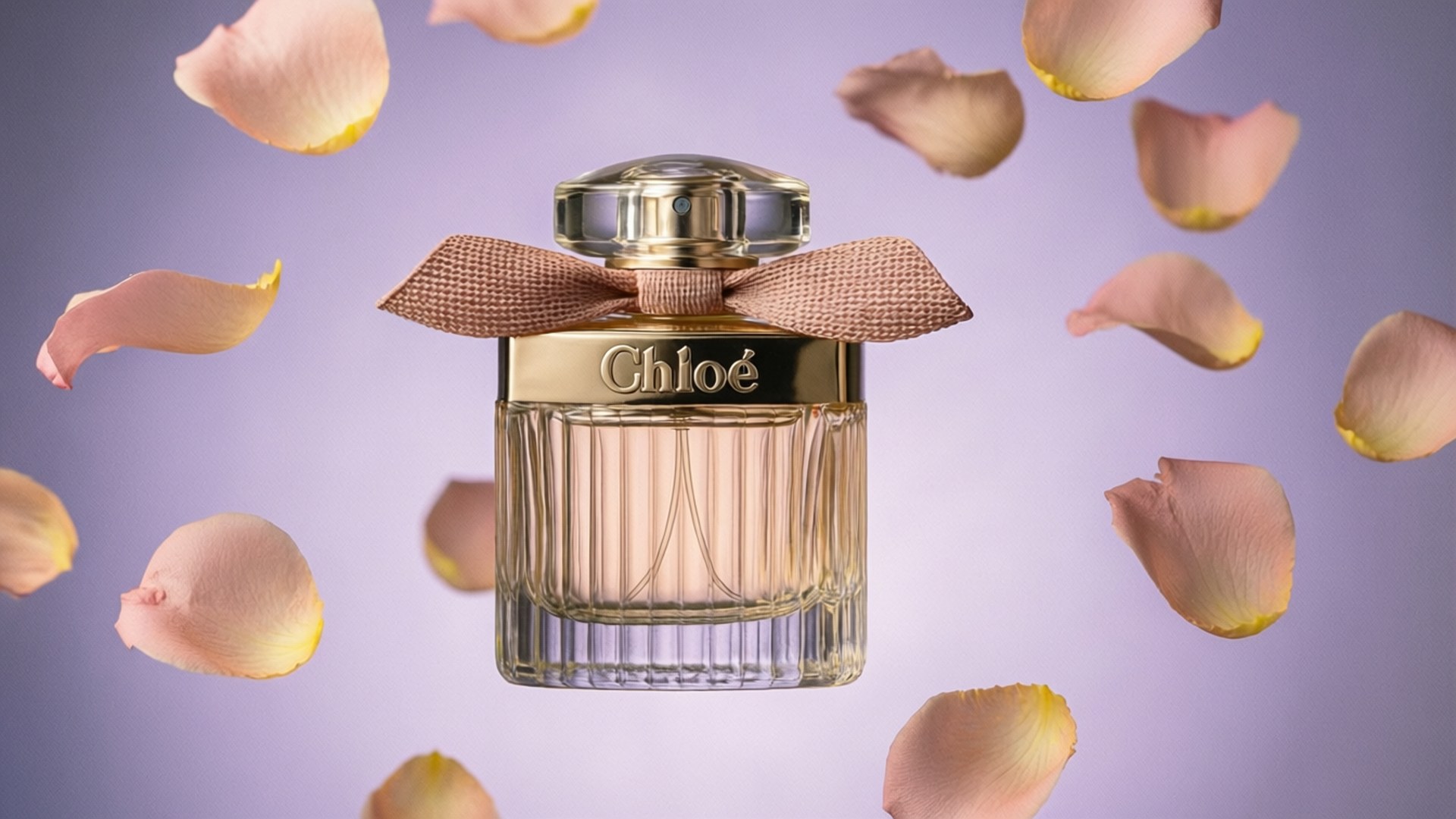 Chloé Perfume with Petals 壁紙 — 一個帶有金色蝴蝶結的Chloe香水瓶漂浮在柔和的薰衣草背景上，周圍環繞著飄落的蜜桃花瓣。