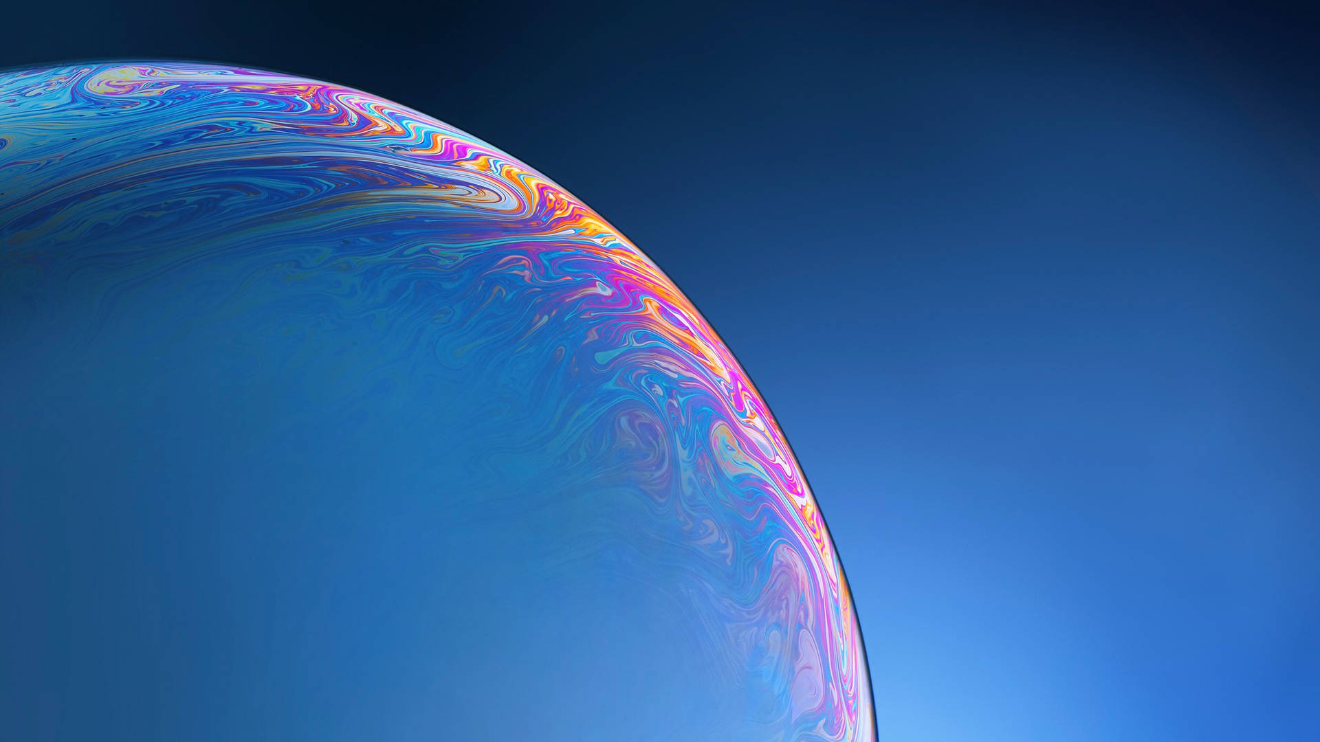 一個色彩繽紛的肥皂泡在藍天中漂浮。 — iPhone 11 壁紙
