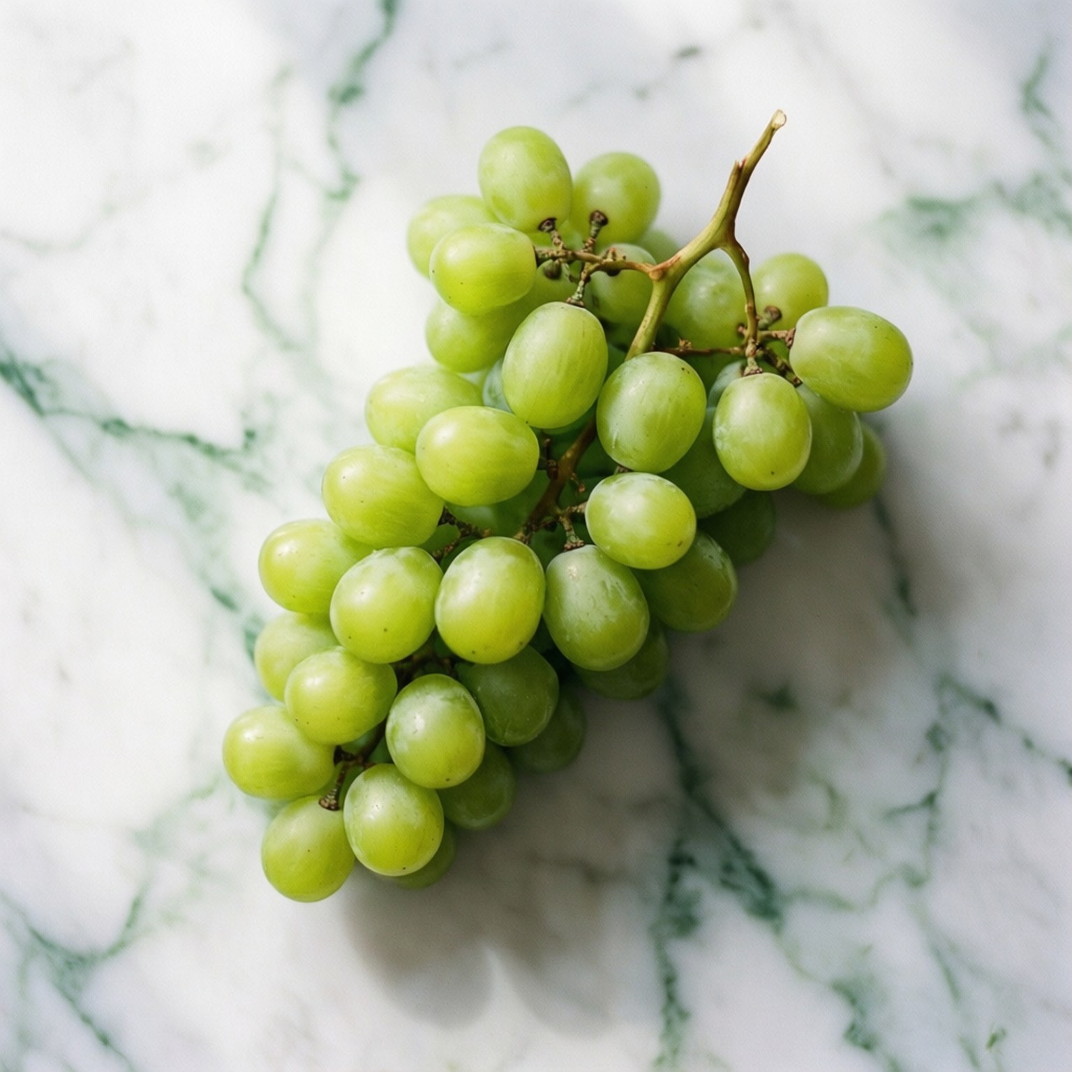 Green Grapes Flat Lay 壁紙 — 一串新鮮的青葡萄放在帶有綠色紋理的白色大理石表面上。
