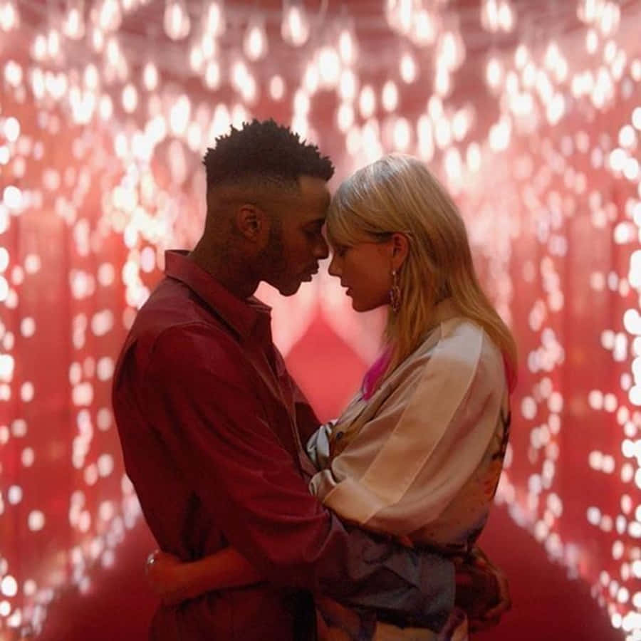 Taylor Swift Lover 桌布 壁紙 — 一對情侶在紅光閃爍的隧道中溫柔擁抱，額頭相觸，共享親密時刻。