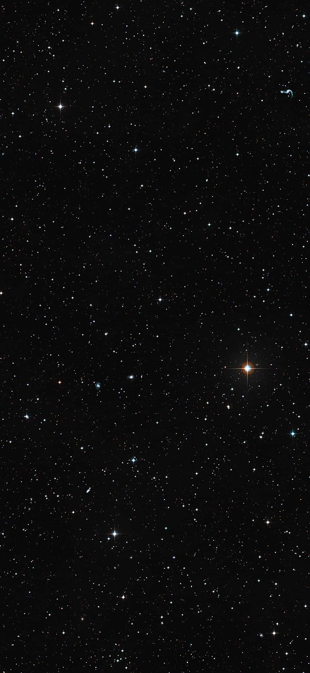 繁星點點的夜空，右下角附近有一顆明亮的橙色星星在發光。 — iPhone 13 Pro 壁紙