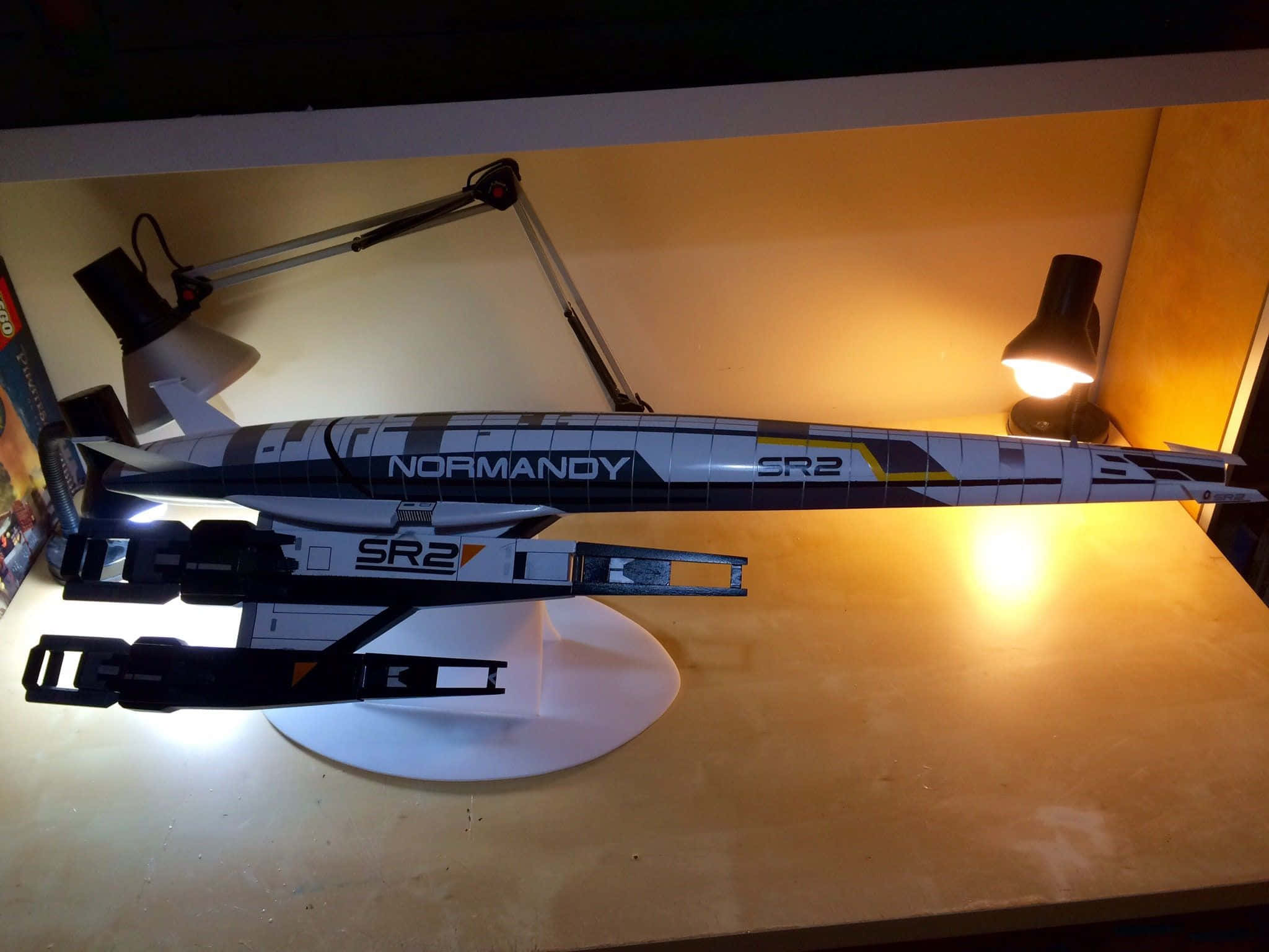 Normandy Sr-2 桌布 壁紙 — 一個詳細的諾曼第SR2太空船模型放在桌子上，在溫暖的桌燈下投射出柔和的陰影。