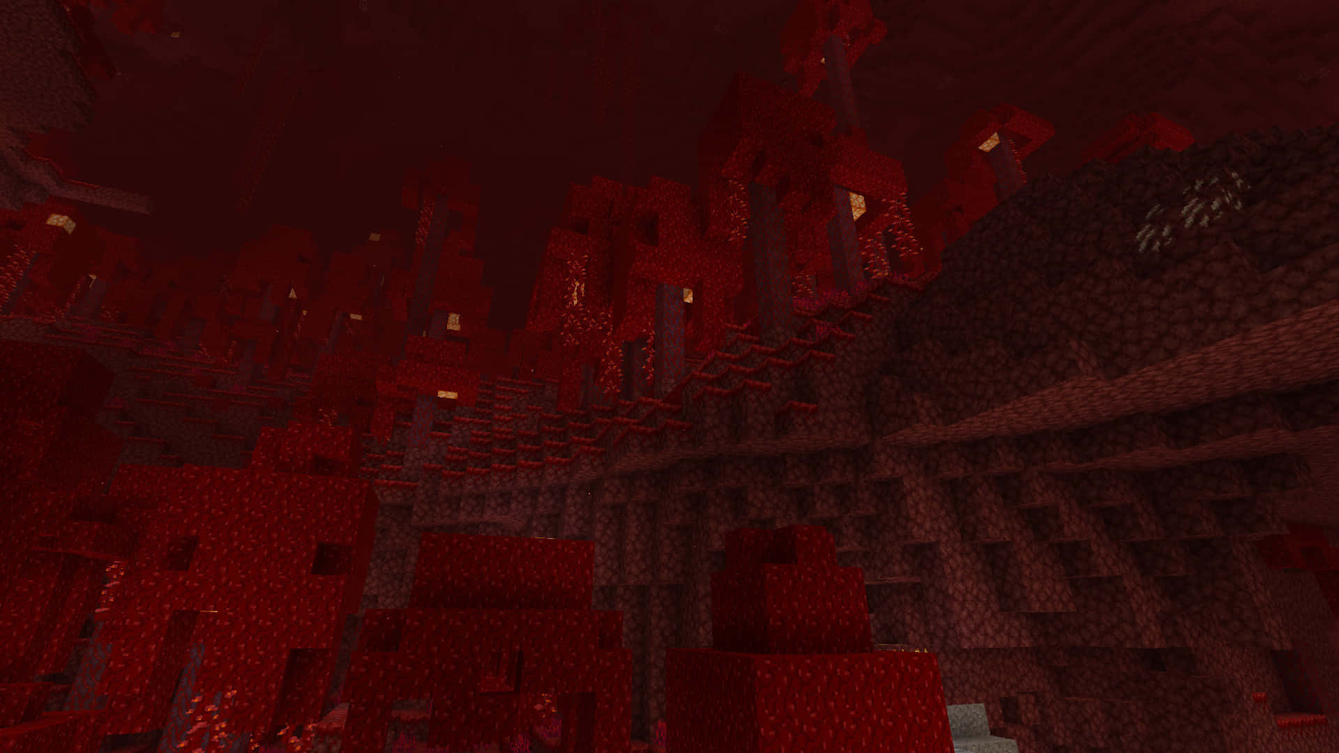  壁紙 — 一個燈光昏暗的Minecraft地獄堡壘，有鋸齒狀的紅色方塊和發光的地獄火火炬。
