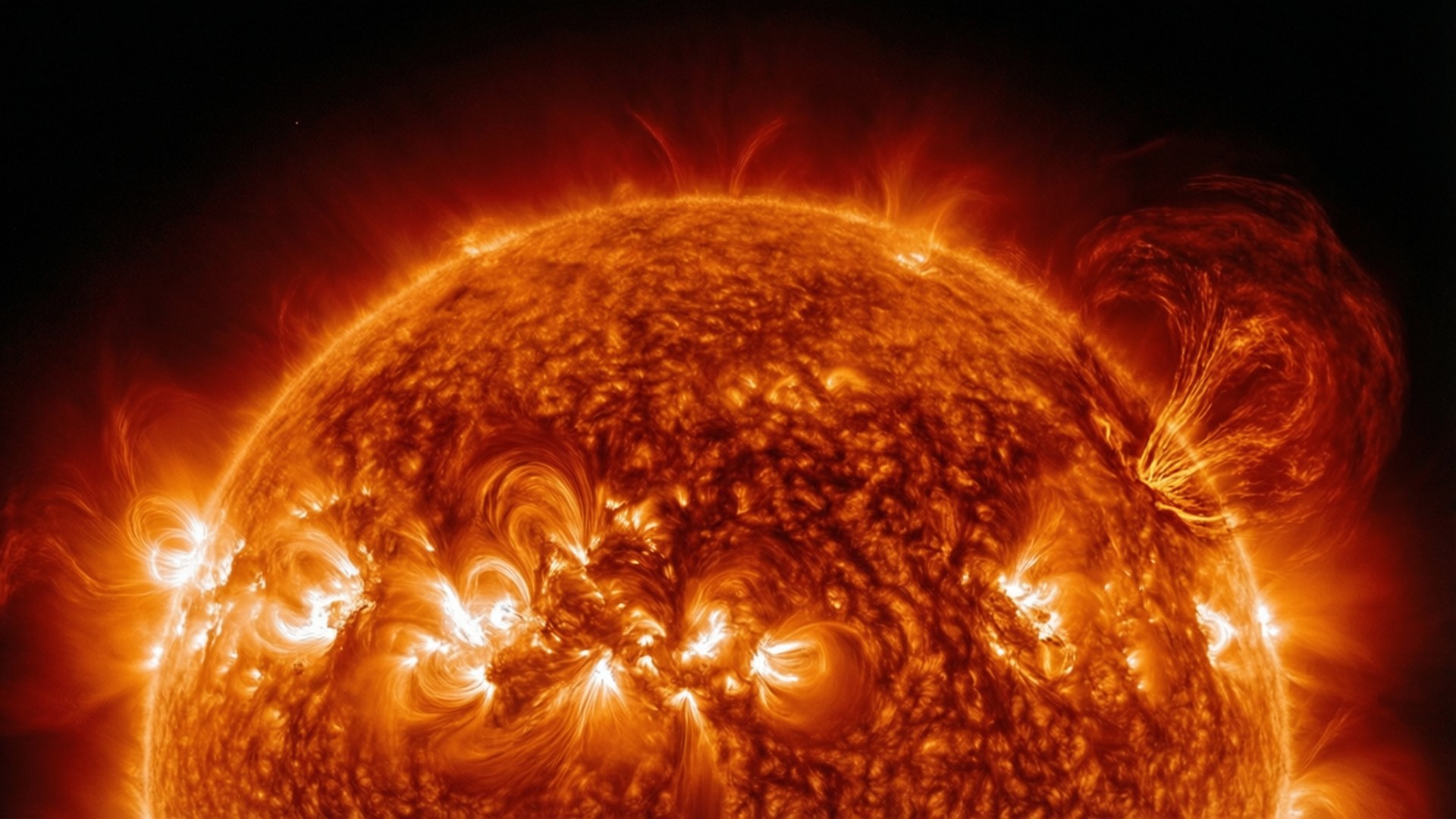 Solar Flare 壁紙 — 一個熾熱的太陽，帶有旋轉的橙色電漿和明亮的太陽耀斑，在黑色虛空中爆發。