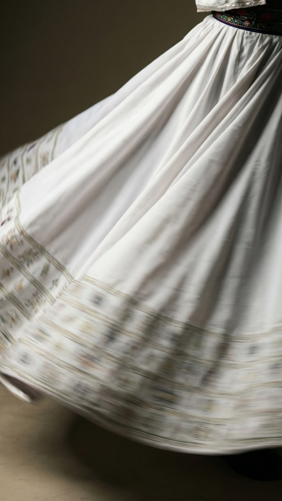 Dervish Skirt Motion 壁紙 — 一條飄逸的白色裙子，帶有精緻的刺繡，在柔和的棕色背景下旋轉時動態地旋轉。