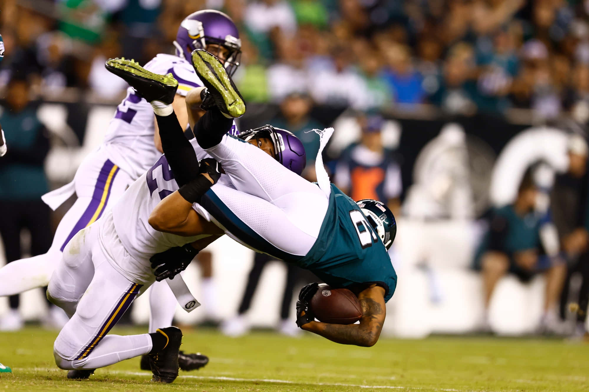 Devonta Smith 桌布 壁紙 — 一名身穿藍綠色球衣的美式足球員向後飛撲接球，而一名身穿白色球衣的防守員在燈光球場上跳起試圖擒抱他。