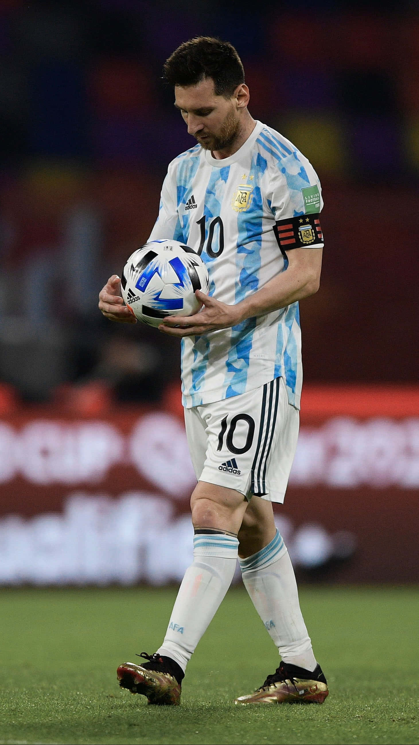 Messi 2022 桌布 壁紙 — 阿根廷足球巨星梅西身穿藍白條紋球衣，在明亮的燈光下於球場上手持足球。