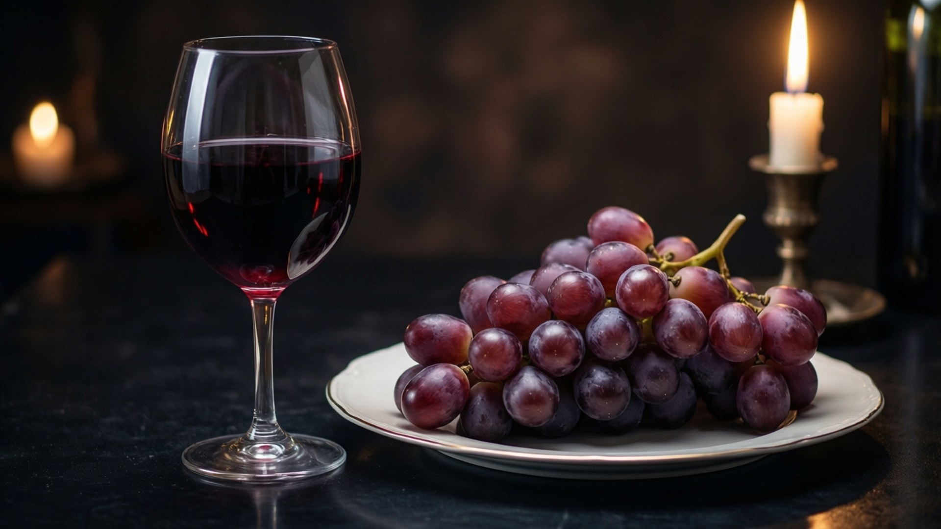 Romantic Wine and Grapes 壁紙 — 一杯紅酒和一盤紫葡萄放在一張暗色桌子上，旁邊有燃燒的蠟燭散發出溫暖的光芒。