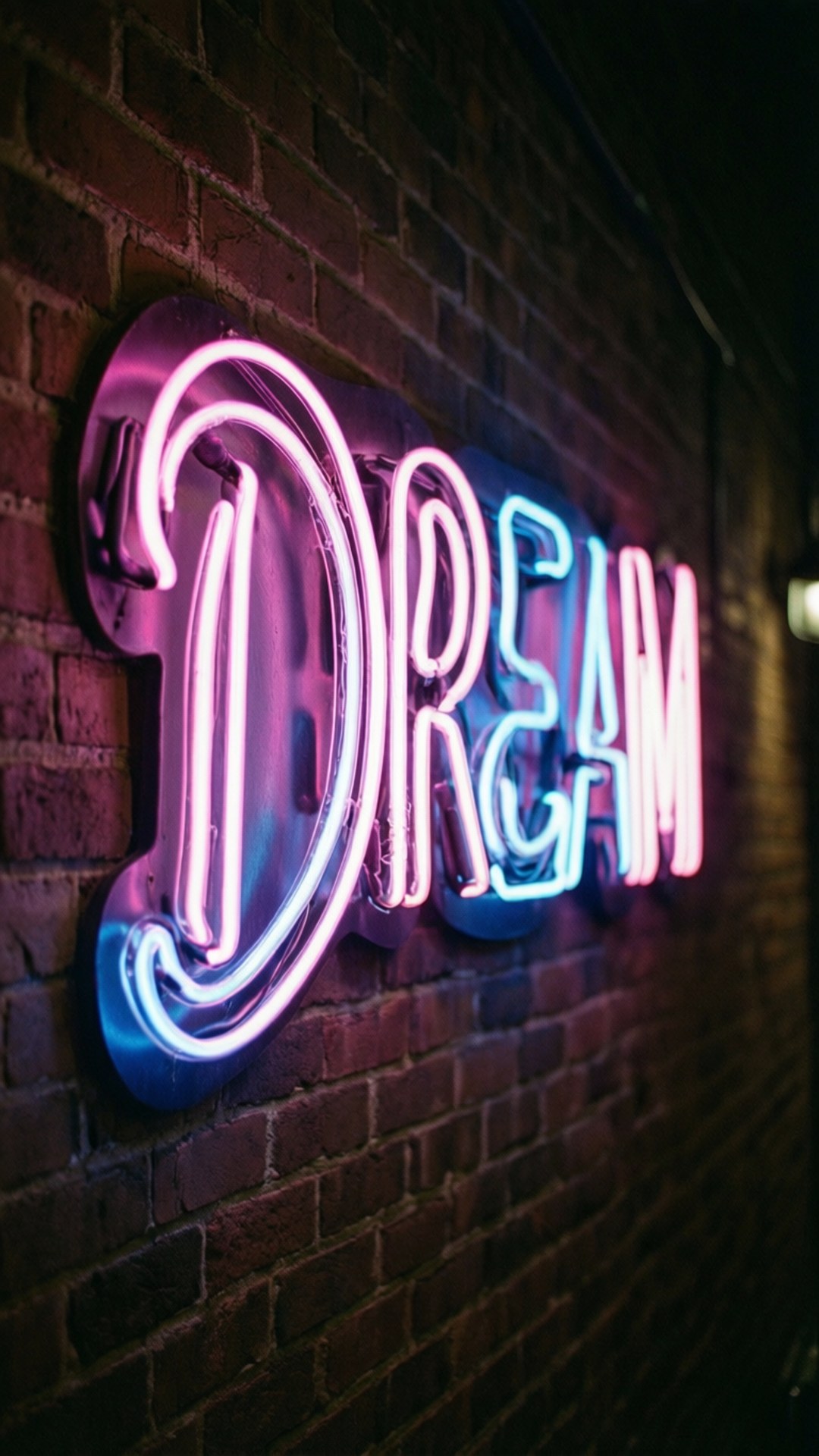 Dream Sign 壁紙 — 一個發光的霓虹燈牌，用粉紅色和藍色拼出「DREAM」，安裝在深色磚牆上。