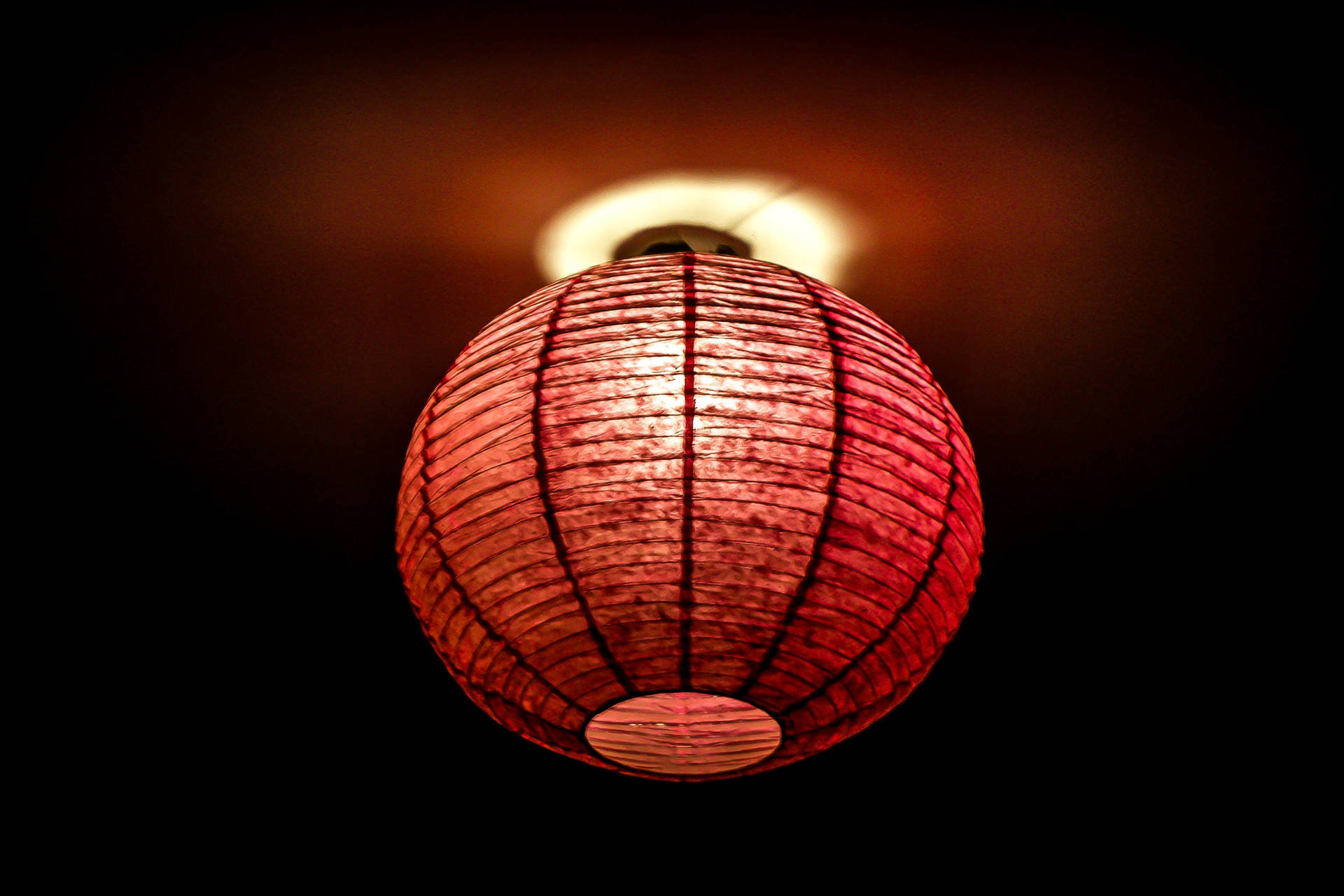 一個紅色紙燈籠在黑暗的天花板上溫暖地發光。 — 春節 壁紙
