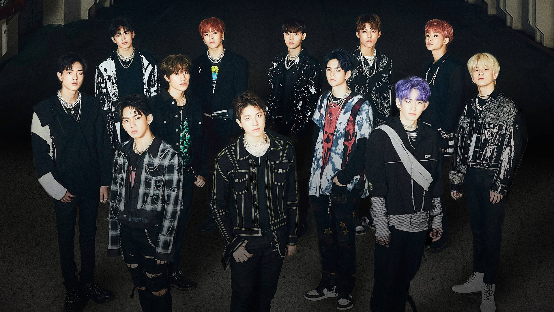 K-pop 團體在黑暗的城市小巷中擺姿勢，擁有色彩繽紛的頭髮和時尚服裝。 — Jungkook 壁紙