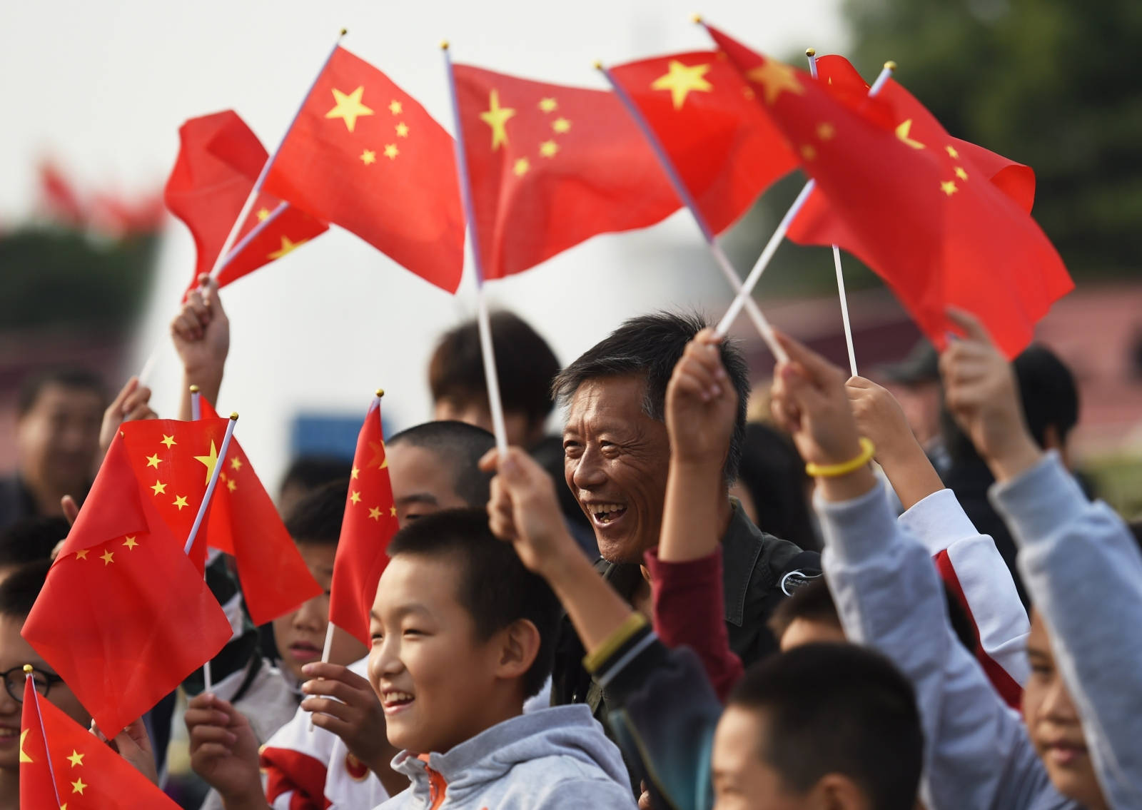 人群在戶外帶著歡樂的表情揮舞中國國旗。 — 中國國旗 壁紙