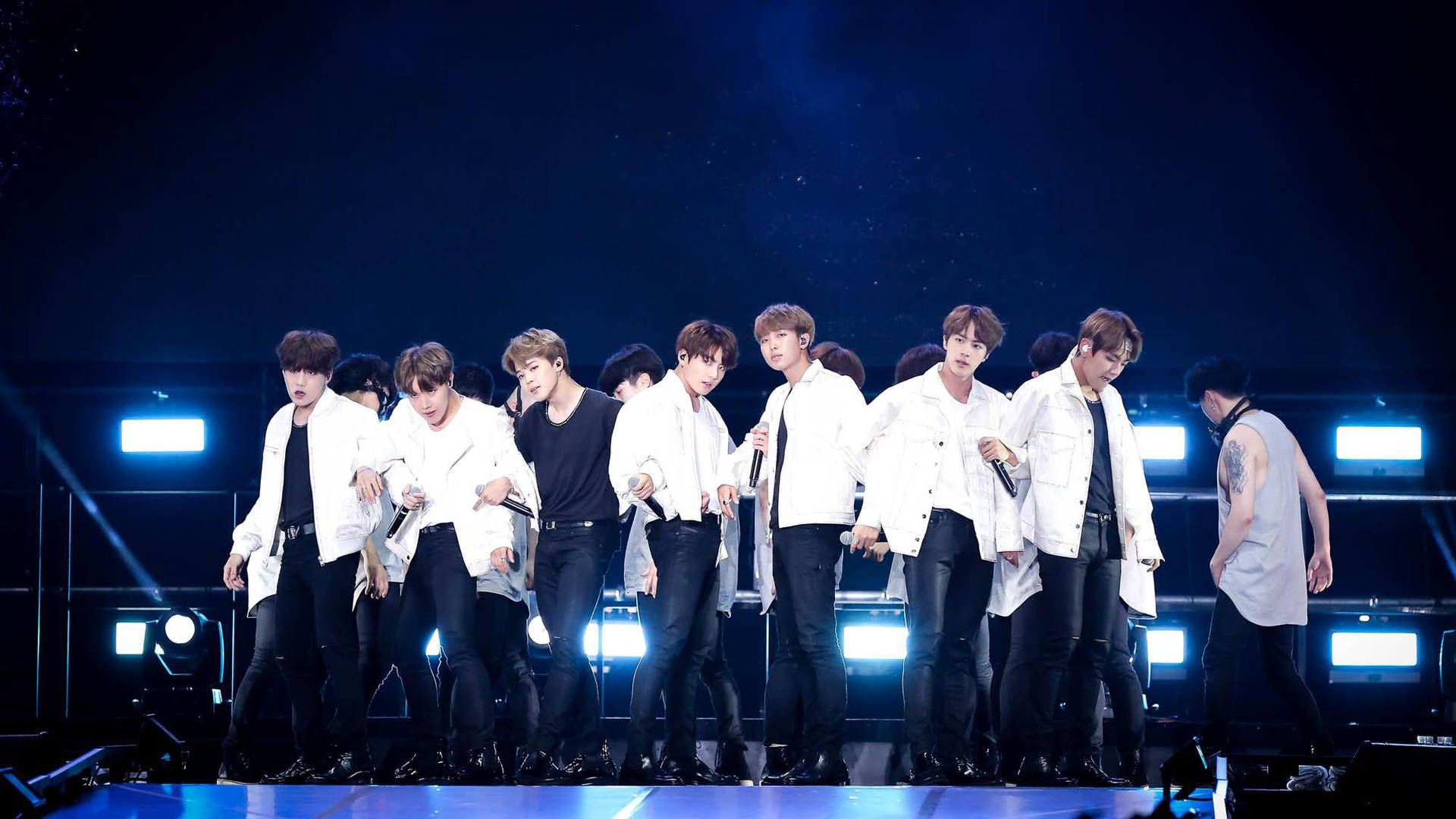 K-pop組合在藍色聚光燈和煙霧中於明亮的舞台上跳舞。 — Bts 壁紙