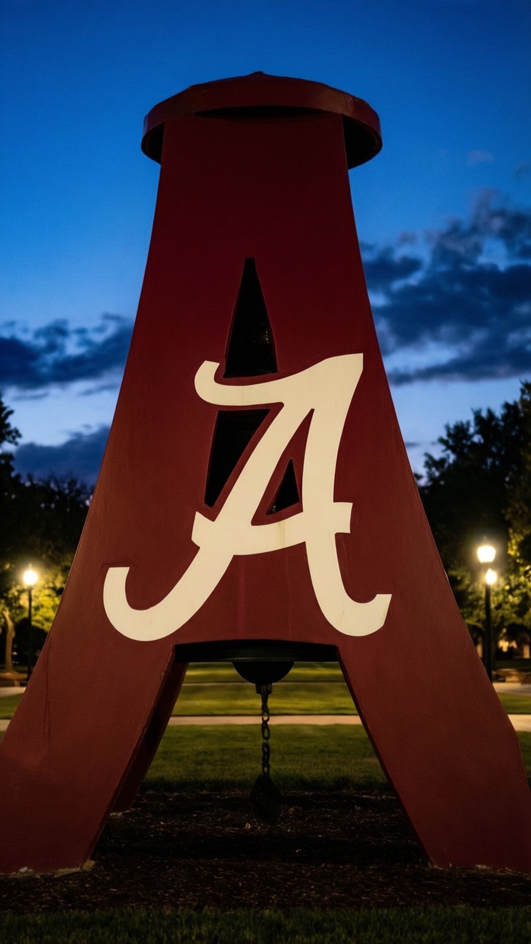 Denny Chimes Night Glow 壁紙 — 一座巨大的深紅色鐘樓，上面有一個白色的草書字母A，在暮色天空和散雲的映襯下熠熠生輝。