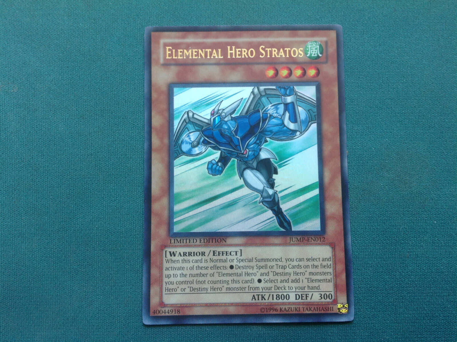 Yugioh Elemental Hero 桌布 壁紙 — 一張限量版遊戲王卡牌， featuring Elemental Hero Stratos 身穿動感藍色盔甲，背景為帶條紋的綠色。