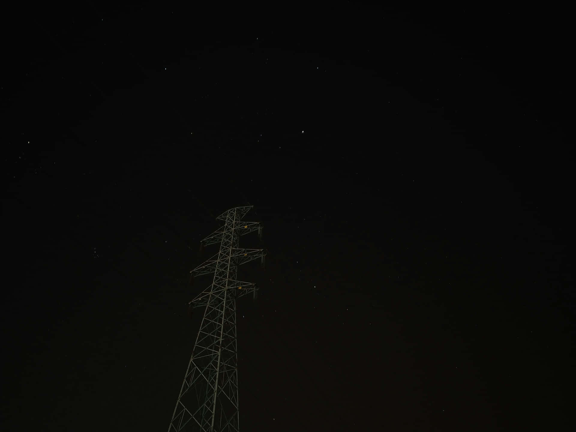  壁紙 — 一座孤獨的輸電塔在繁星點點的夜空下呈現剪影。