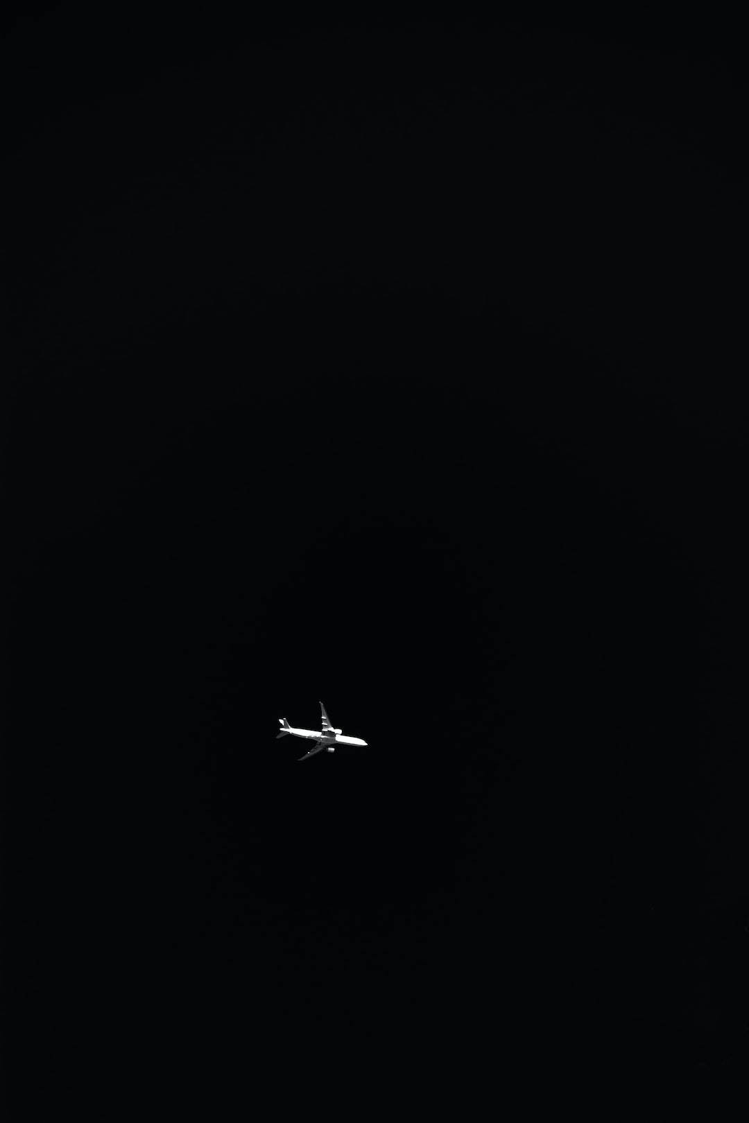 一架飛機獨自在黑暗的夜空中飛行。 — 簡約 壁紙