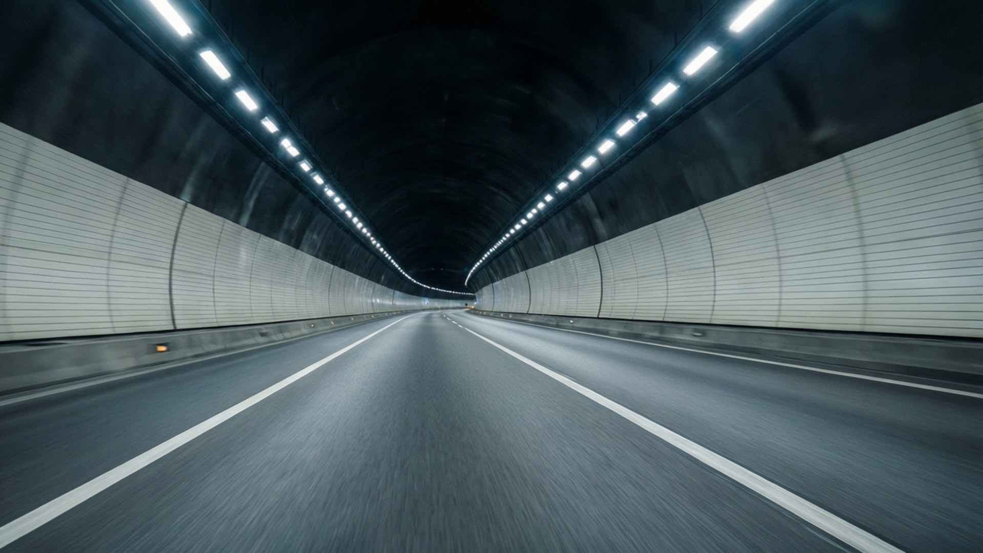 Light Tunnel 壁紙 — 一條長直隧道，白色牆壁和頭頂燈光在黑暗的道路上逐漸消失在遠方。