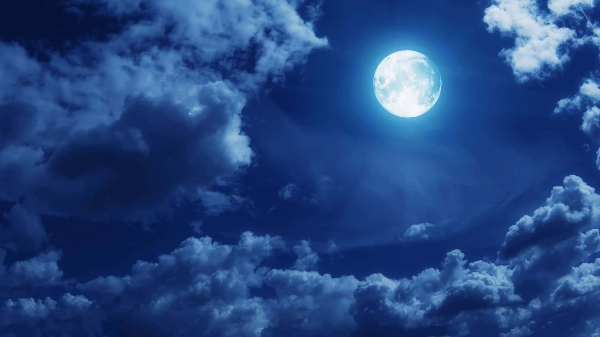 Moon Night 桌布 壁紙 — 一輪明亮的滿月透過旋轉的深藍色雲層在戲劇性的夜空中閃耀。