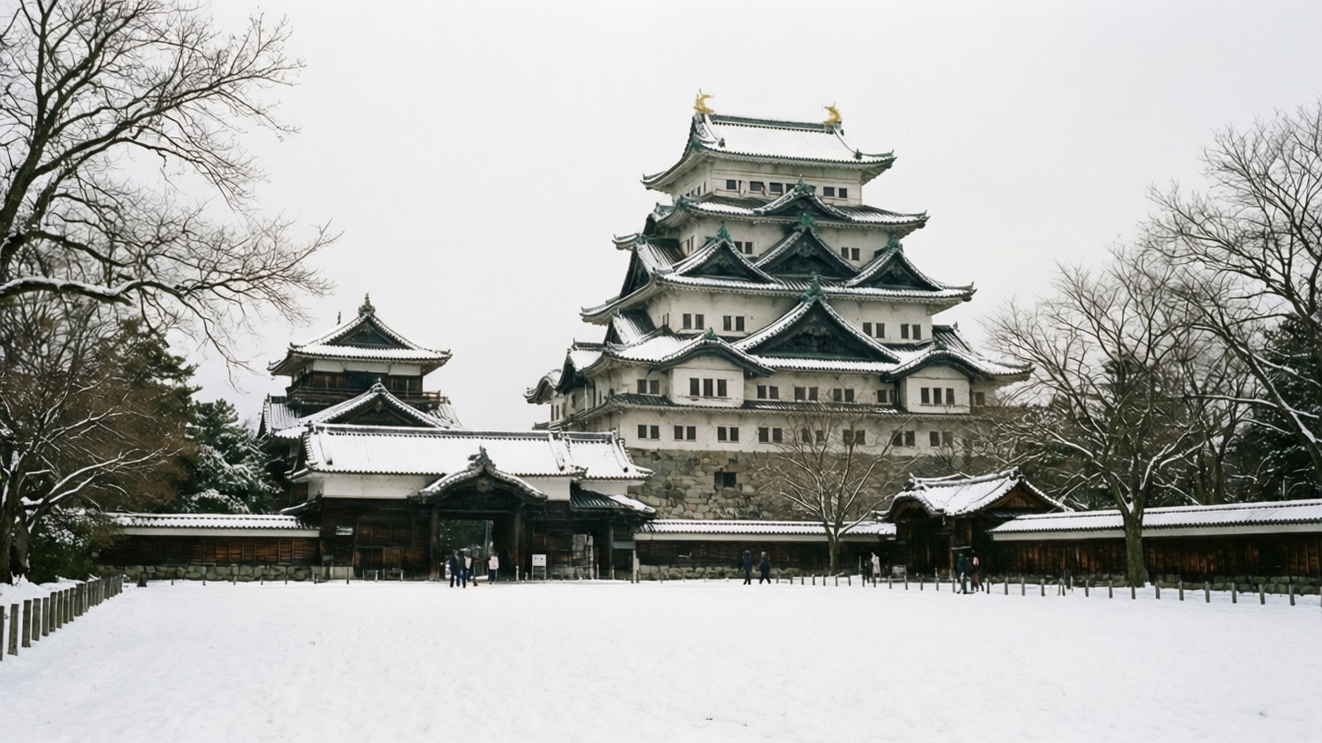 Winter Nagoya Castle 壁紙 — 一座雄偉的雪覆蓋的日本城堡，擁有分層屋頂和石牆，在灰色的冬日天空下寧靜地矗立。