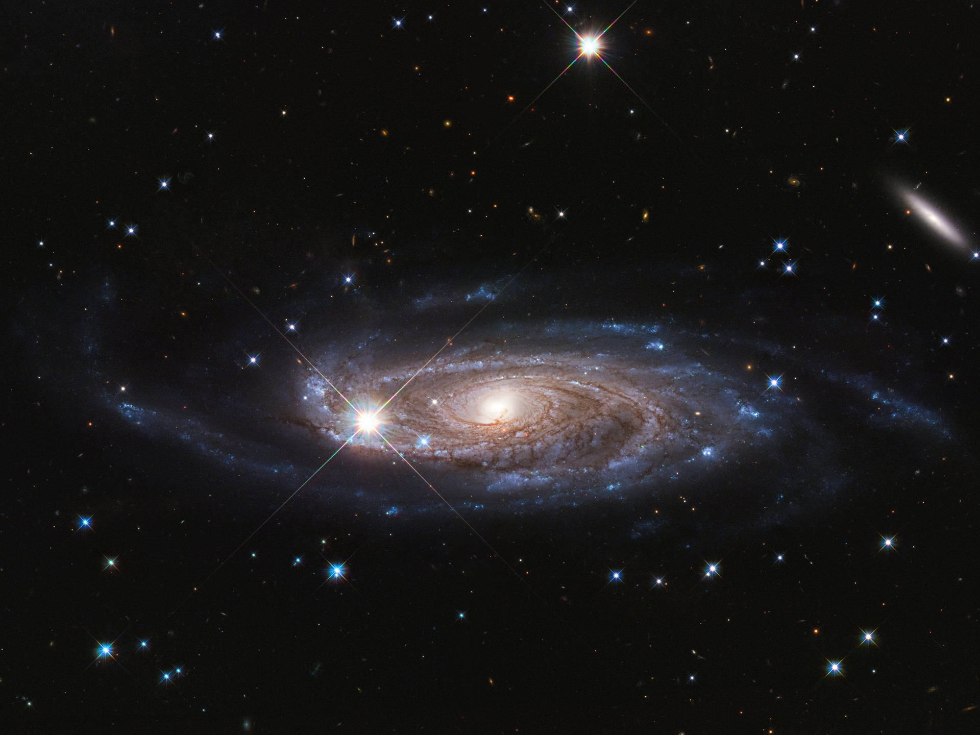 一個在深空中帶有明亮星星和發光旋臂的螺旋星系。 — 太空 壁紙